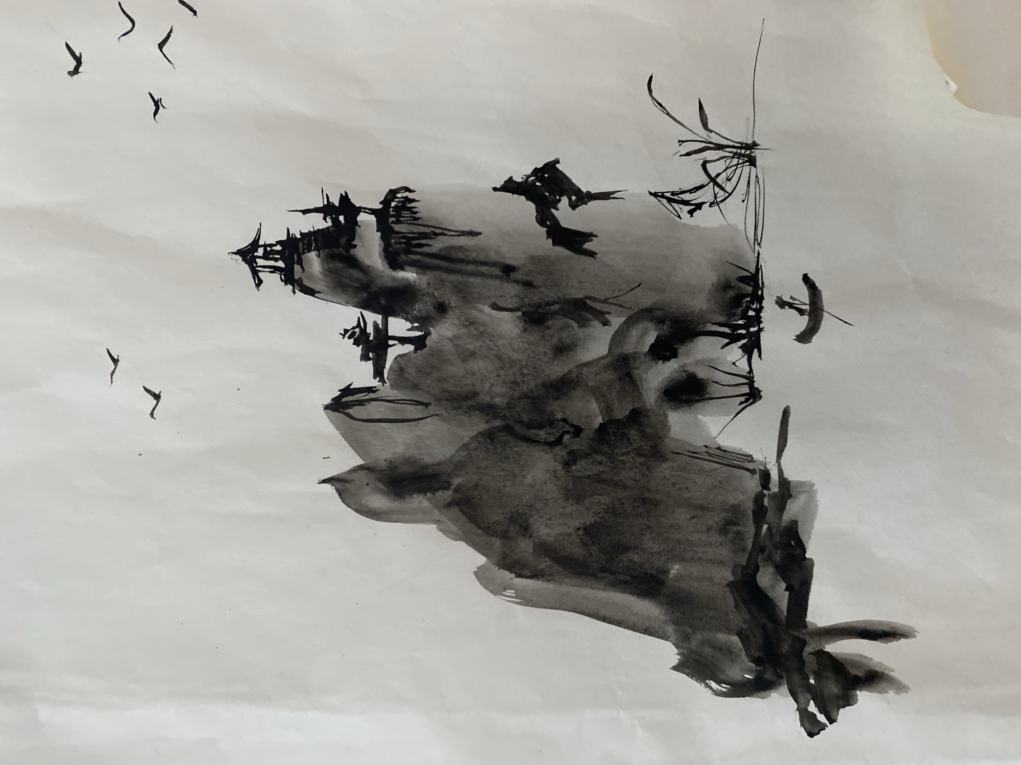 This minimalist ink wash painting, rendered in shades of black ink on a light, textured paper, depicts a serene and atmospheric East Asian landscape. A prominent, dark, and organically shaped mass dominates the center, likely representing a stylized mountain, cliff, or forested island. This central form is created with varying ink washes, giving it depth and suggesting a misty or watery environment around its edges.
Within and upon this dark mass, finer, sharper black ink strokes outline what appear to be traditional architectural structures, possibly temples or pagodas, interspersed with sparse, angular elements that suggest trees or dense vegetation. Above and to the left, several small, calligraphic strokes represent birds in flight, adding a dynamic element and a sense of scale to the expansive, light-toned background that serves as the sky or mist. Delicate, vertical lines on the far right hint at reeds or tall grasses.
The scene conveys a sense of tranquility and solitude, with no explicit activity taking place. The soft washes and stark contrasts suggest an atmospheric setting, possibly a misty morning or a contemplative evening. The style evokes traditional East Asian aesthetics, aligning with the natural beauty often found in regions like Lâm Viên - Đà Lạt, Vietnam. No text is visible in the image.