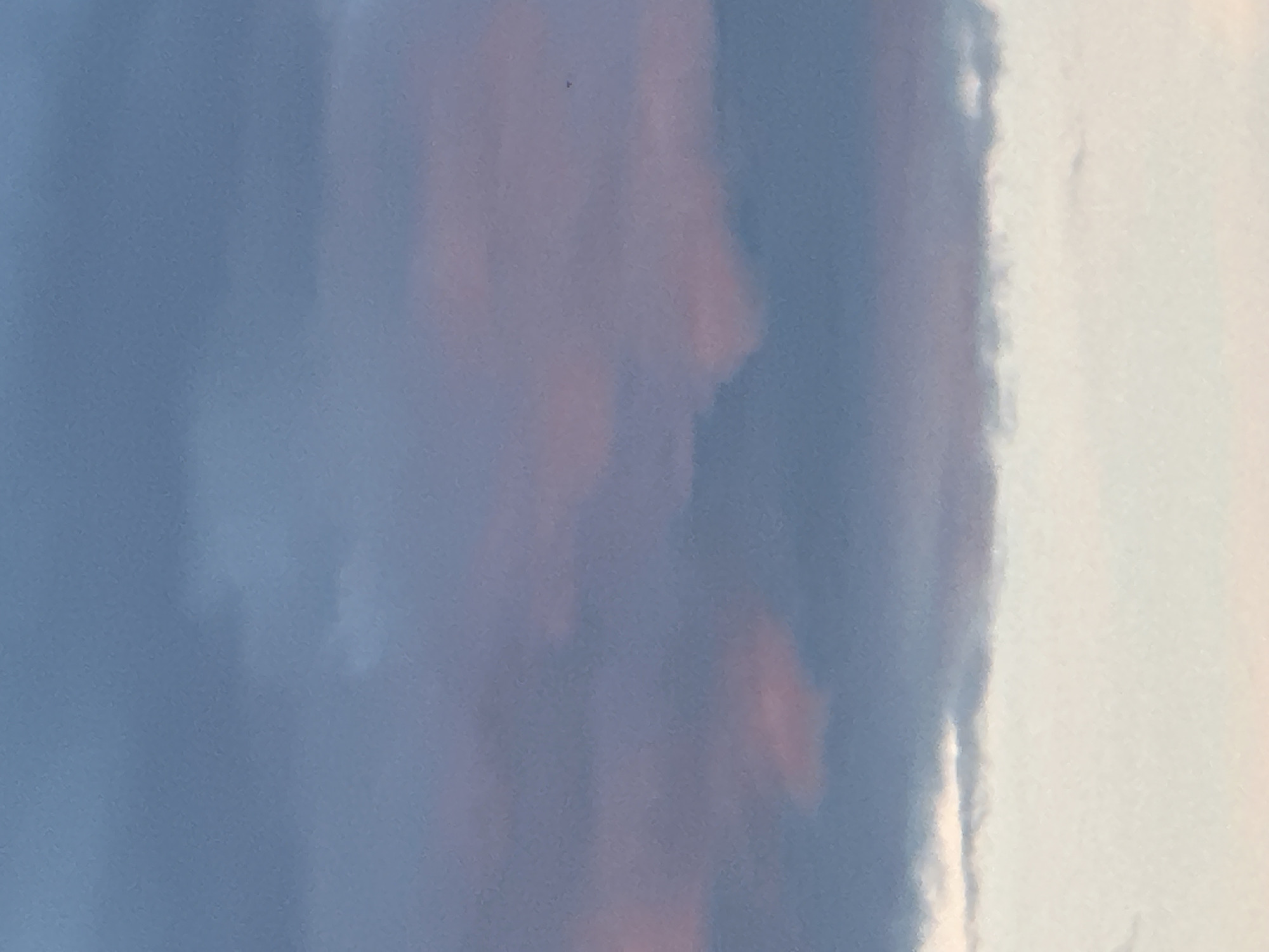 The image depicts a cloudy sky with streaks of pink and purple visible within the gray clouds. The lower portion of the image is a lighter, almost white sky, possibly indicating the horizon or a break in the clouds. There are no visible structures, people, or objects in the image. The scene is solely focused on the sky and its atmospheric conditions. The location in Nizhny Novgorod, Russia, is not determinable from the visual information provided in the image.