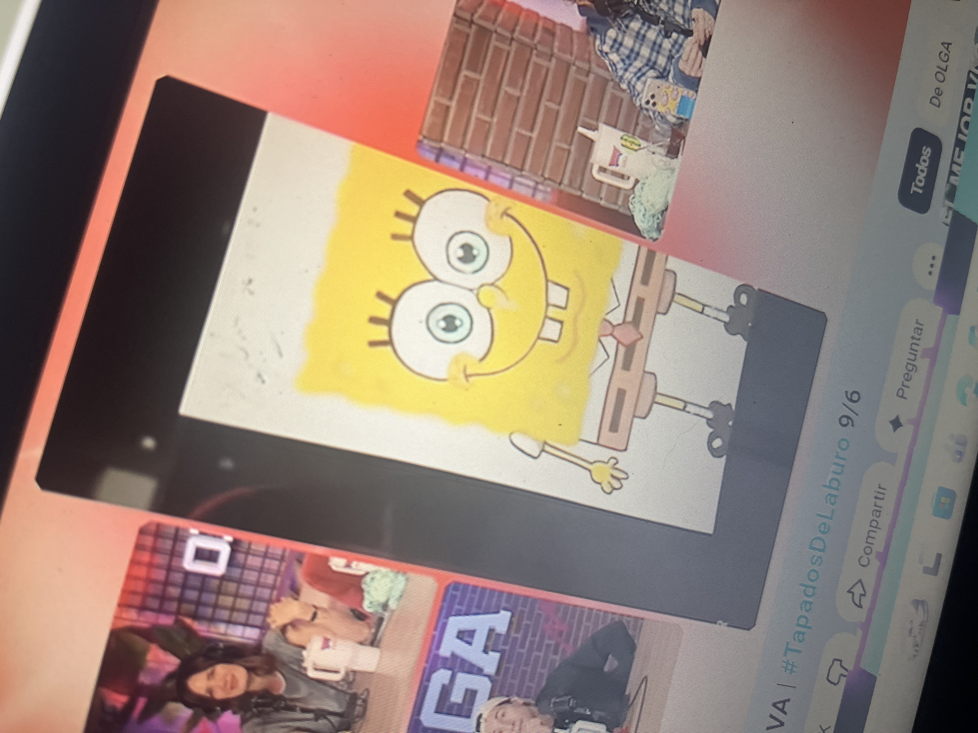 The image displays a computer screen showing a video conference or streaming platform. In the foreground, a Spongebob Squarepants character is depicted in a drawing style. To the left of the Spongebob image, there are two smaller video feeds. The left feed shows a woman with dark hair wearing headphones and a grey striped shirt, holding a white mug. Behind her is a grid-like structure with a white square symbol. The right feed, partially obscured, shows a person wearing a blue and white plaid shirt, sitting in front of a brick wall. The bottom of the screen shows interface elements such as "Compartir," "Preguntar," and "Todos." The image context does not provide any information about the city of Santa Ana, Venezuela.