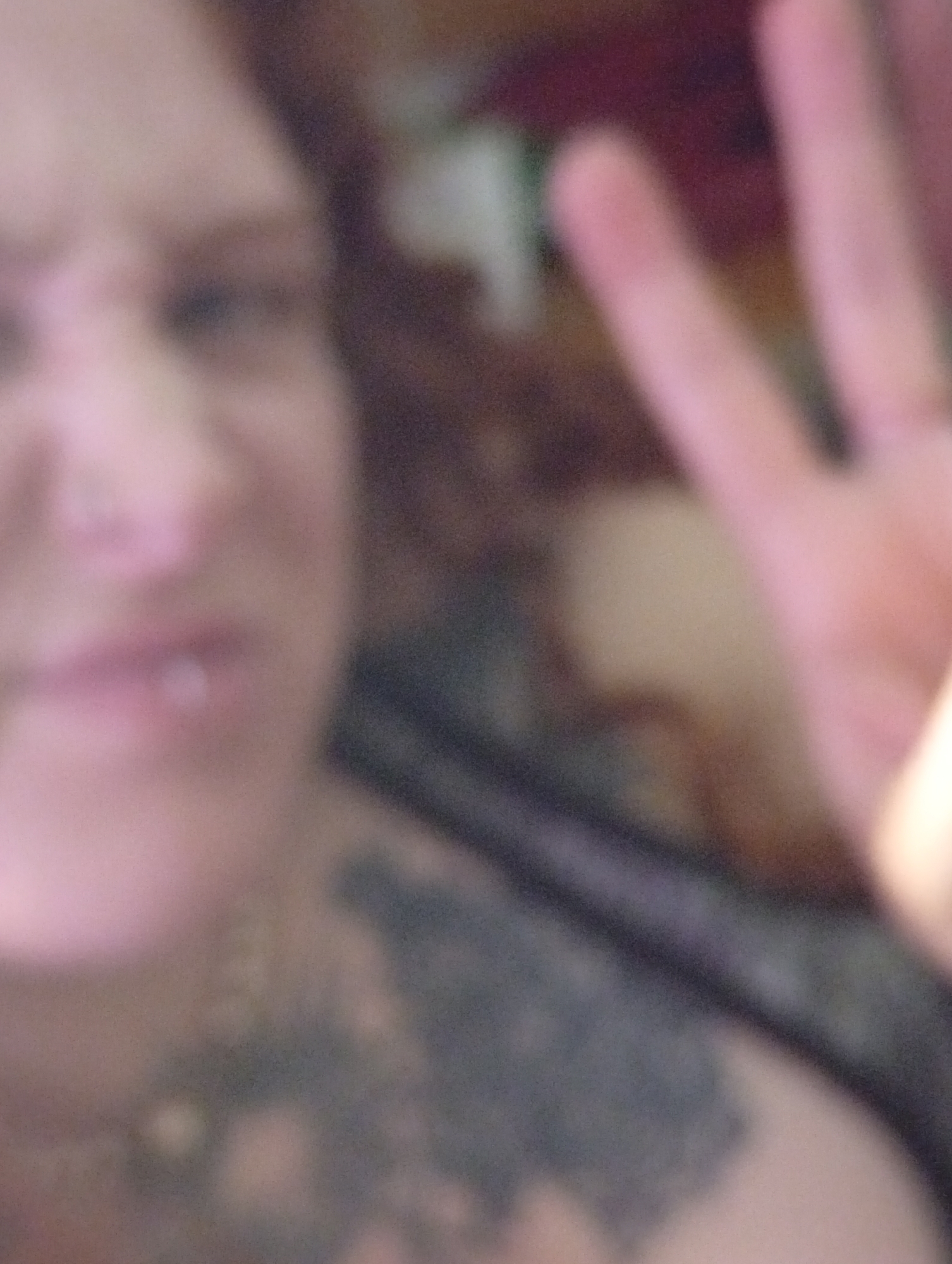 A blurry image shows a person with a dark neck tattoo and a possible lip piercing holding up four fingers. The background is indistinct but suggests an indoor setting. The city and specific location in Buenos Aires, Argentina, cannot be determined from this image.