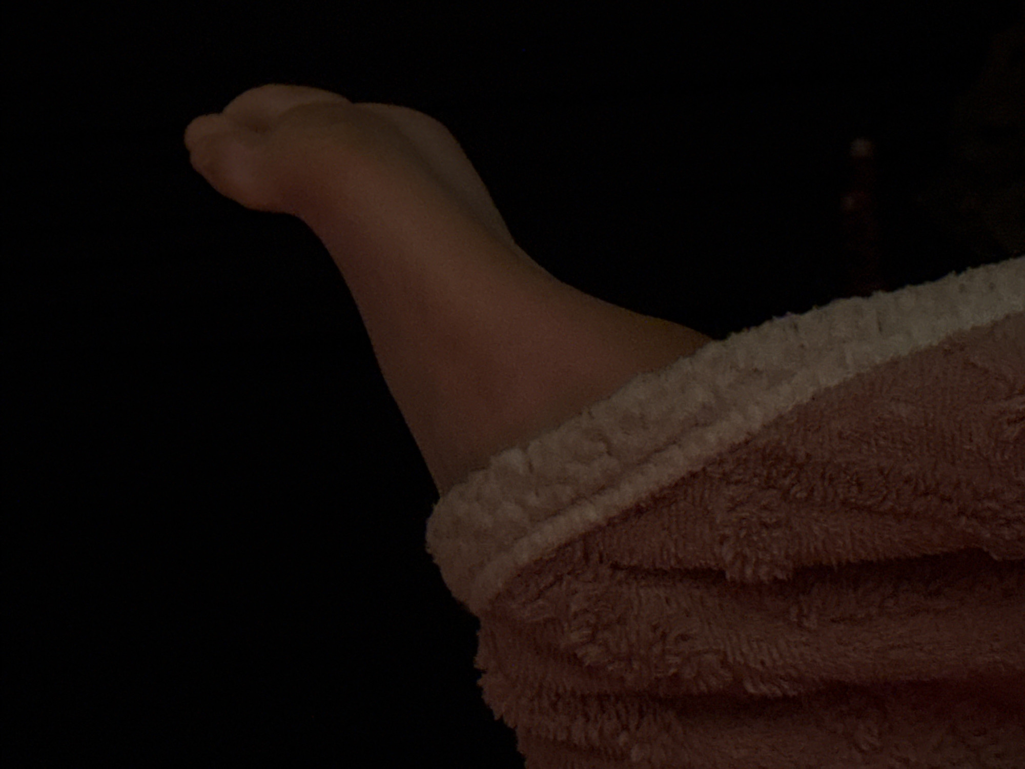 A person's arm and hand protrude from the sleeve of a pink, fluffy robe against a dark background. The hand is clenched into a fist. The scene is undetailed, with the arm and robe the primary focus. There is no indication of the location being Budva, Montenegro.