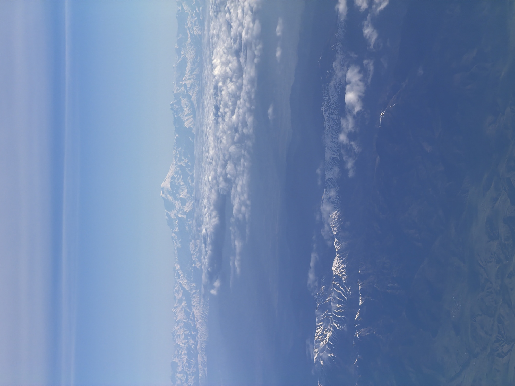 The image shows a view of a mountain range from above. Patches of snow are visible on the peaks. There is also a large cloud formation situated between the mountains.
The image does not show the location of Dolgoprudny, Russia.