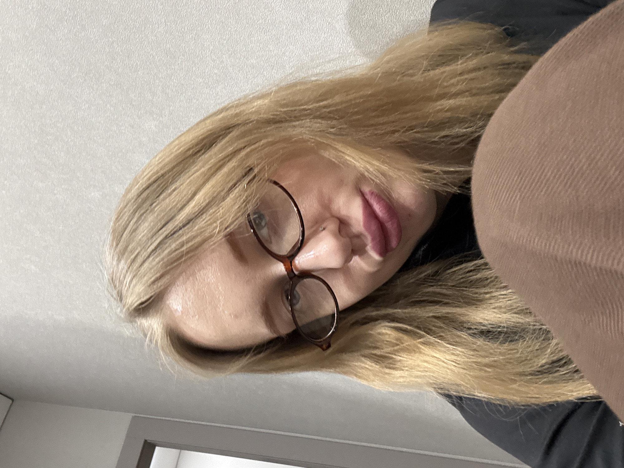 A blonde-haired person wearing eyeglasses is lying on a light-colored surface, possibly a bed or floor. The person is wearing a dark-colored shirt and brown pants. The location is unspecified, and there is no indication in the image that it is in Kuleshovka, Russia.