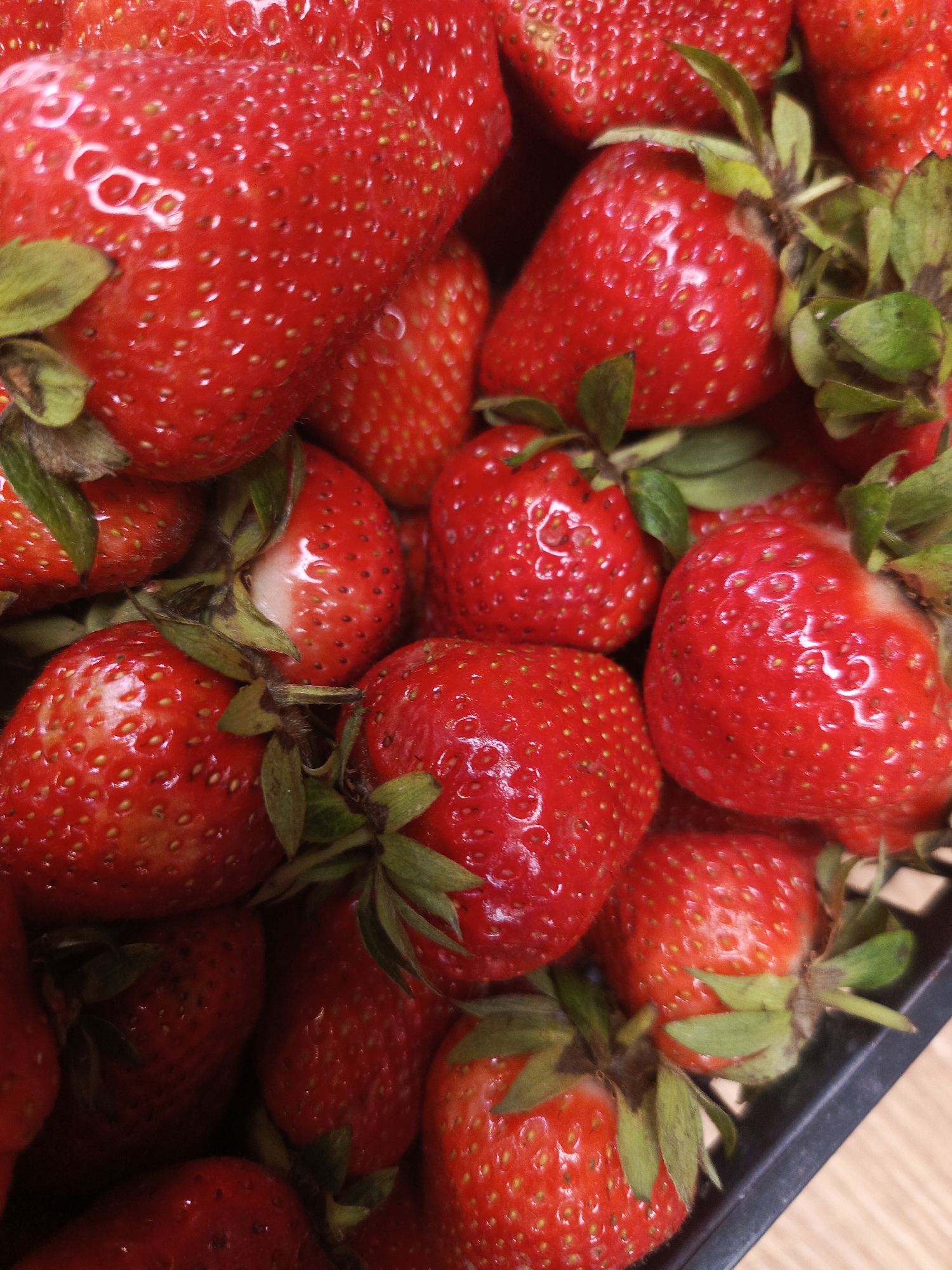 A close-up, overhead shot shows a pile of ripe, red strawberries. The berries are plump and glossy, with visible seeds and green leafy tops. Some of the strawberries are partially obscured by others. The overall impression is one of freshness and abundance. There is no discernible location in Chaikovsky, Russia, as the image focuses exclusively on the fruit.