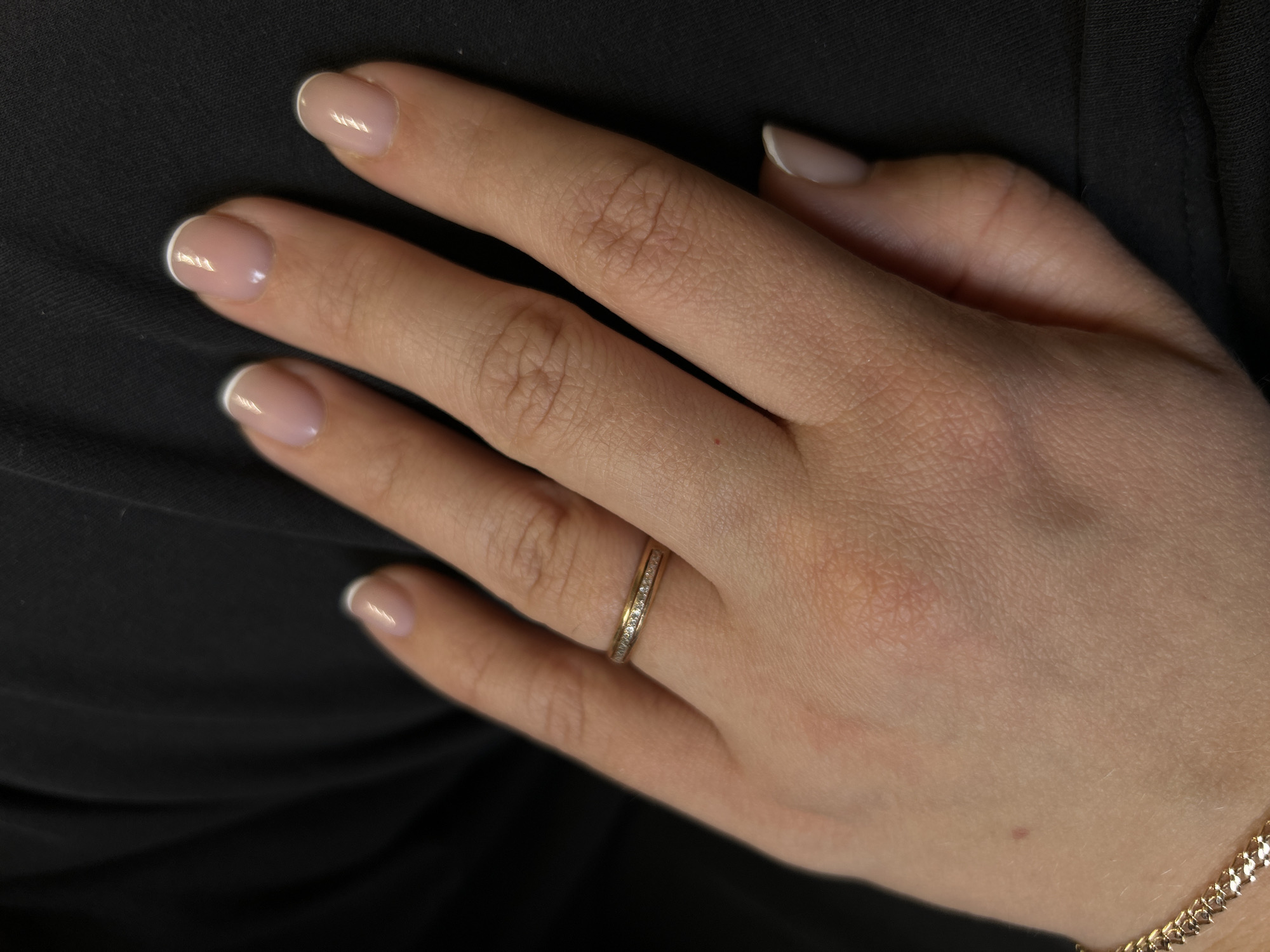 A photograph depicts a woman's hand resting on a black fabric surface, likely clothing. The hand features neatly manicured nails with a classic French tip design. A gold ring with inset stones is worn on the ring finger. The hand and ring are the primary subjects. The location is not discernible from the image, and the mention of Ural'skoe, Russia appears unrelated.