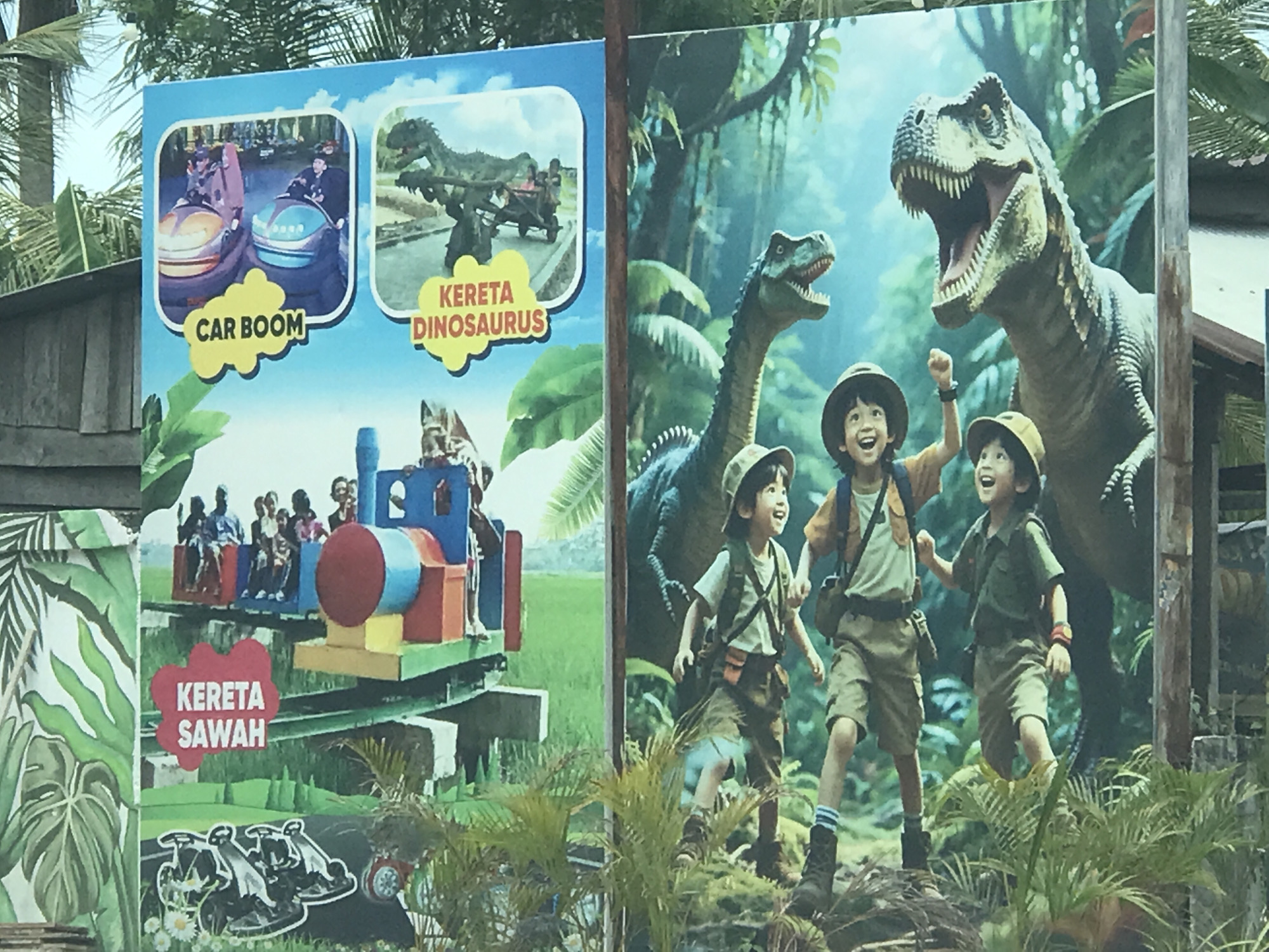 The image depicts two adjacent signs advertising amusement park attractions in Lhokseumawe, Indonesia. The left sign features images of "Car Boom" bumper cars, a "Kereta Dinosaurus" dinosaur ride, and a "Kereta Sawah" train ride. The right sign shows three children dressed as explorers running towards two dinosaurs, a Brachiosaurus and a Tyrannosaurus Rex. The signs are displayed outdoors, and tropical foliage is visible in the foreground.