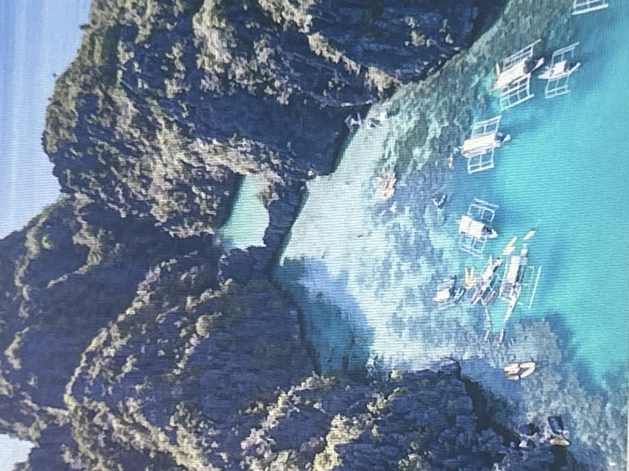 This image is an aerial view of a picturesque tropical cove. Towering, jagged limestone cliffs covered in lush green vegetation surround a tranquil, turquoise lagoon. The water is exceptionally clear, revealing the sandy seabed and coral formations below.
Scattered across the lagoon are numerous traditional outrigger boats, also known as bangkas. These boats are predominantly white with outrigger supports, and some appear to be carrying passengers. The boats are clustered in various parts of the lagoon, suggesting either a gathering point or a popular tourist destination. The overall scene evokes a sense of natural beauty and serenity.
This scene is not located in the city of Sofia, Bulgaria. Sofia is a landlocked capital city and does not have coastal features like tropical coves or lagoons.