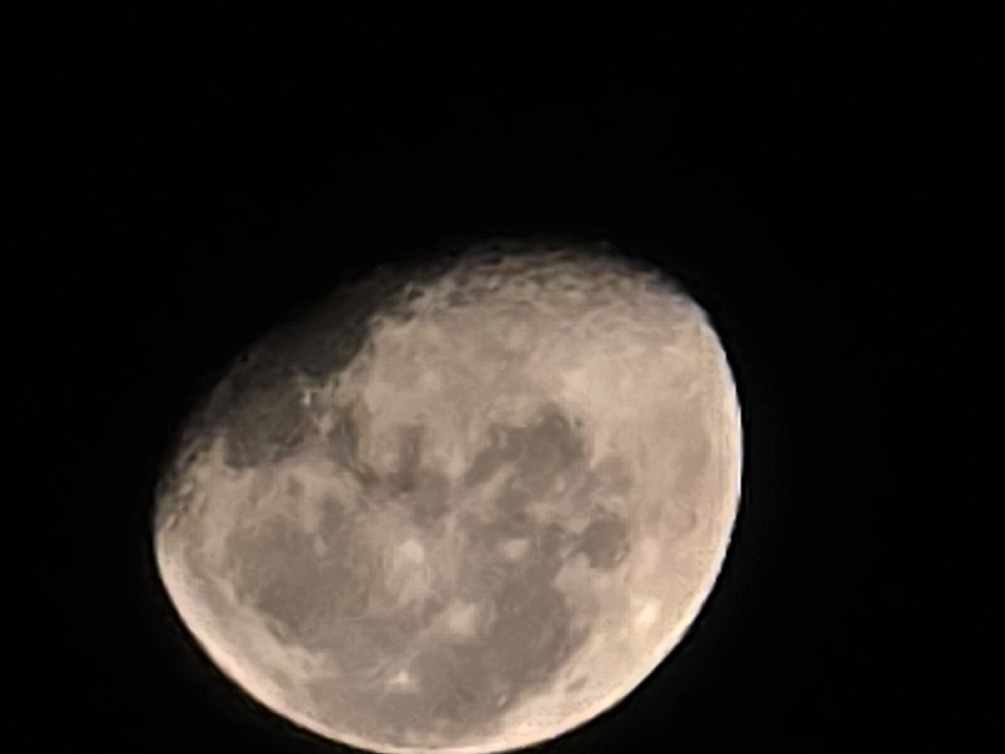 The image is a close-up photograph of the moon against a black sky. The moon is partially illuminated, showing its craters and surface features. The light appears to be coming from the right side of the moon, casting a shadow on the left. The image has a slightly sepia tone. There is no indication of Yambol, Bulgaria, or any other city in the image. The image solely depicts the moon.