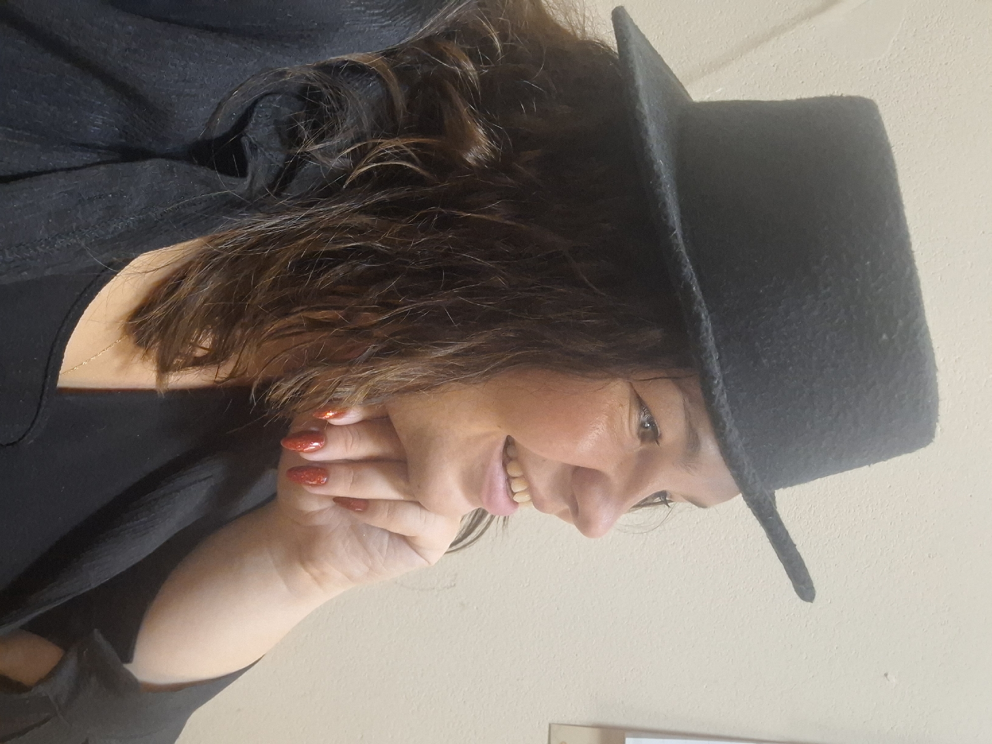 A woman wearing a black hat and black clothing is posing indoors. Her right hand is touching her face. Her nails are painted red. The background appears to be a light neutral wall. It is not possible to verify the location of Markovskii, Russia.