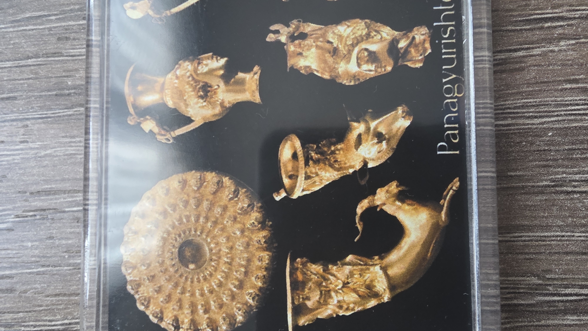 The image shows a close-up of a photograph or printed image of several gold artifacts against a black background. The word "Panagyurishte" is partially visible in white text along the right side of the image. The artifacts appear to be from a historical hoard or collection, and are various vessel-like objects and animal figure representations. The image is possibly from a museum exhibit or publication related to Bulgarian history and goldwork. While the name Panagyurishte is visible, it is not apparent the image is in Blagoevgrad, Bulgaria.