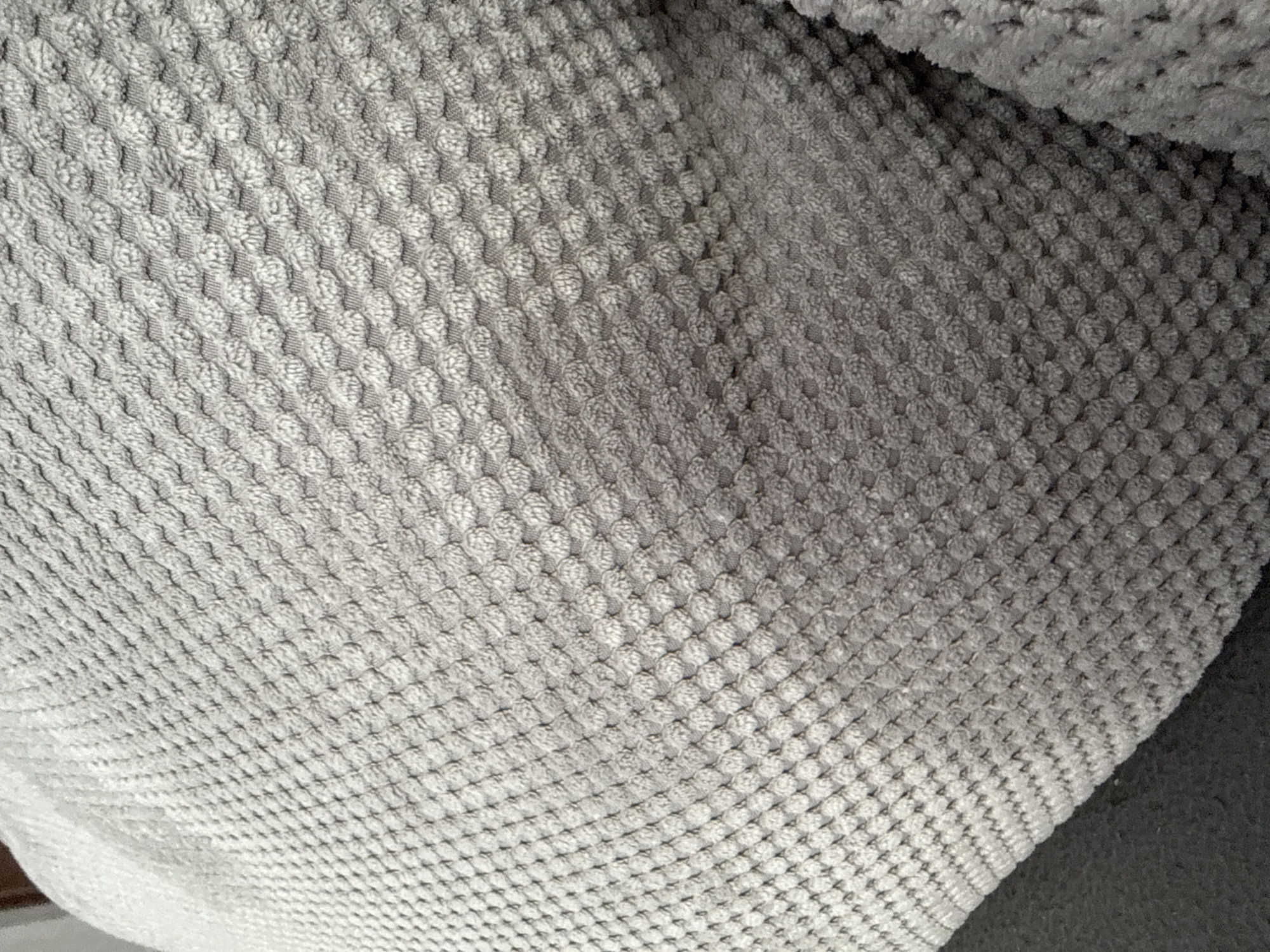 The image shows a close-up of a gray textured fabric with a repeating waffle or honeycomb-like pattern. The material appears soft and has a slightly three-dimensional structure due to the raised texture. There are no people, objects, actions, interactions, or environmental details beyond the fabric itself visible in the image. The location in the city of Lovech, Bulgaria, is not determinable from the image.