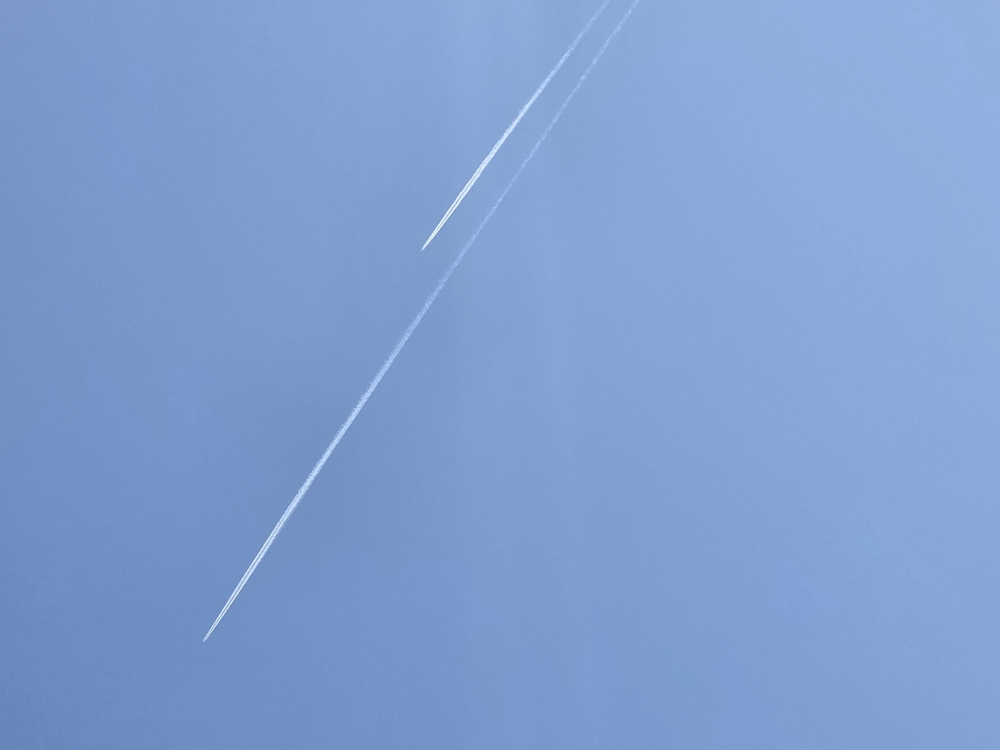 Two airplane contrails are visible in a clear, light blue sky.