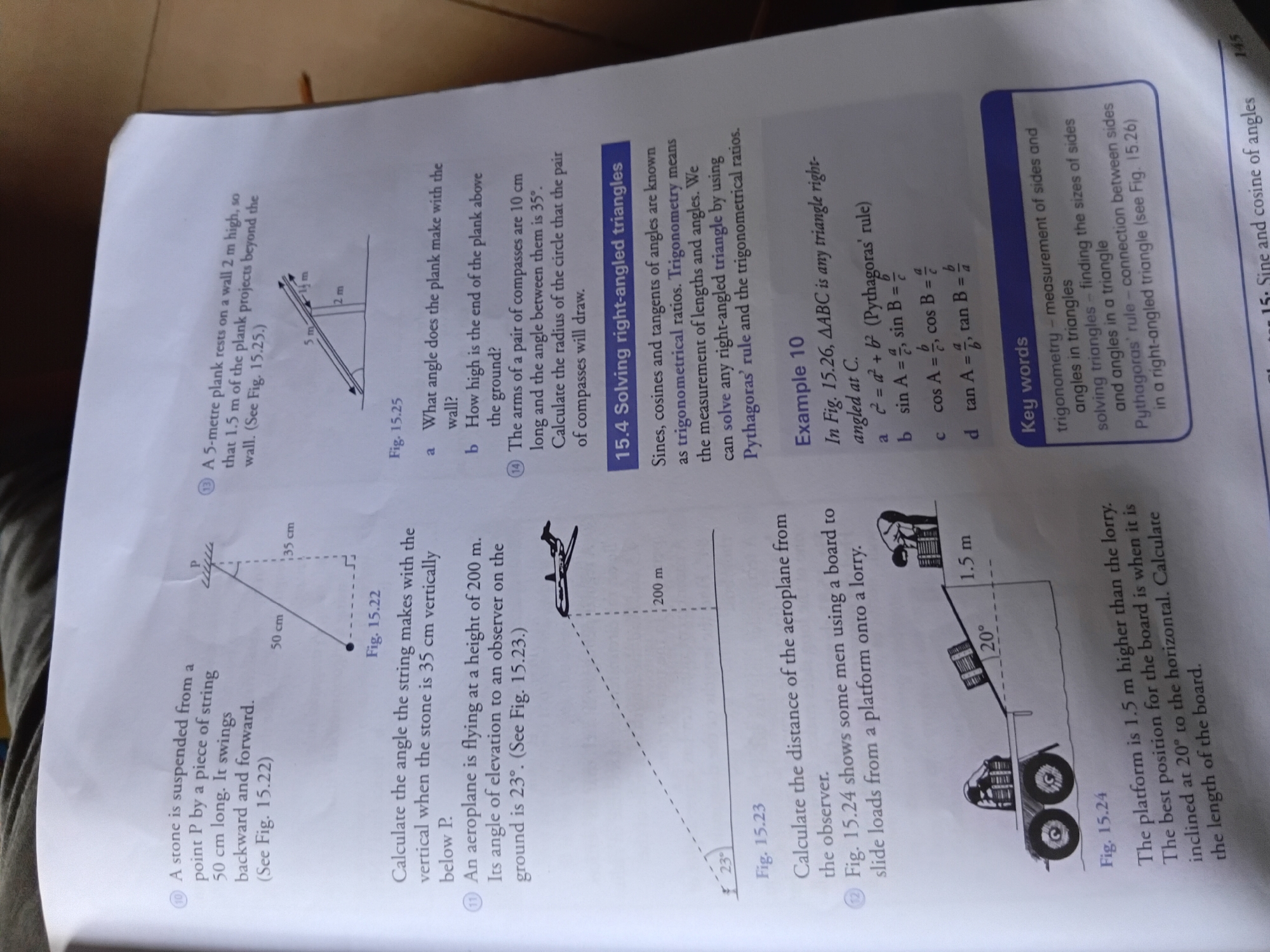 The image is a scanned page from a textbook, likely a math or physics textbook. It contains several word problems with accompanying diagrams. The text is primarily in English. The content focuses on trigonometry and geometry, with problems involving a swinging stone, an airplane's angle of elevation, and a plank resting against a wall. There are also diagrams illustrating these problems. The page number "145" is visible at the bottom right corner. The image is a partial view of a page, with some glare and shadows, suggesting it was photographed. There is no information in the image to suggest a location in Nkpor, Nigeria.