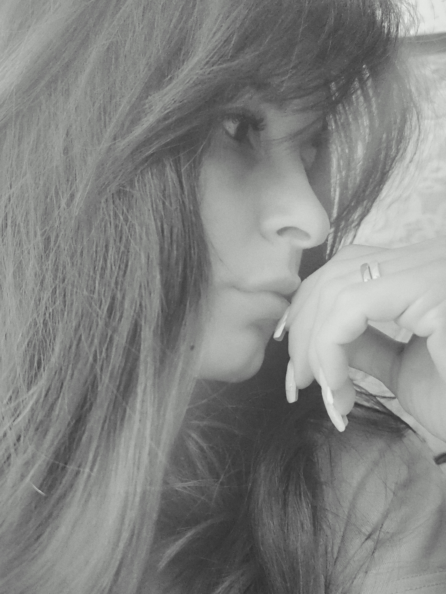 A close-up black and white portrait shows a woman in profile with her face turned slightly towards the camera. Her long hair falls across the left side of the image. She is resting her chin on her hand, and her fingers are visible. A ring is on one of her fingers. The background is nondescript. There is no verifiable information to locate the image in Фоки, Russia.