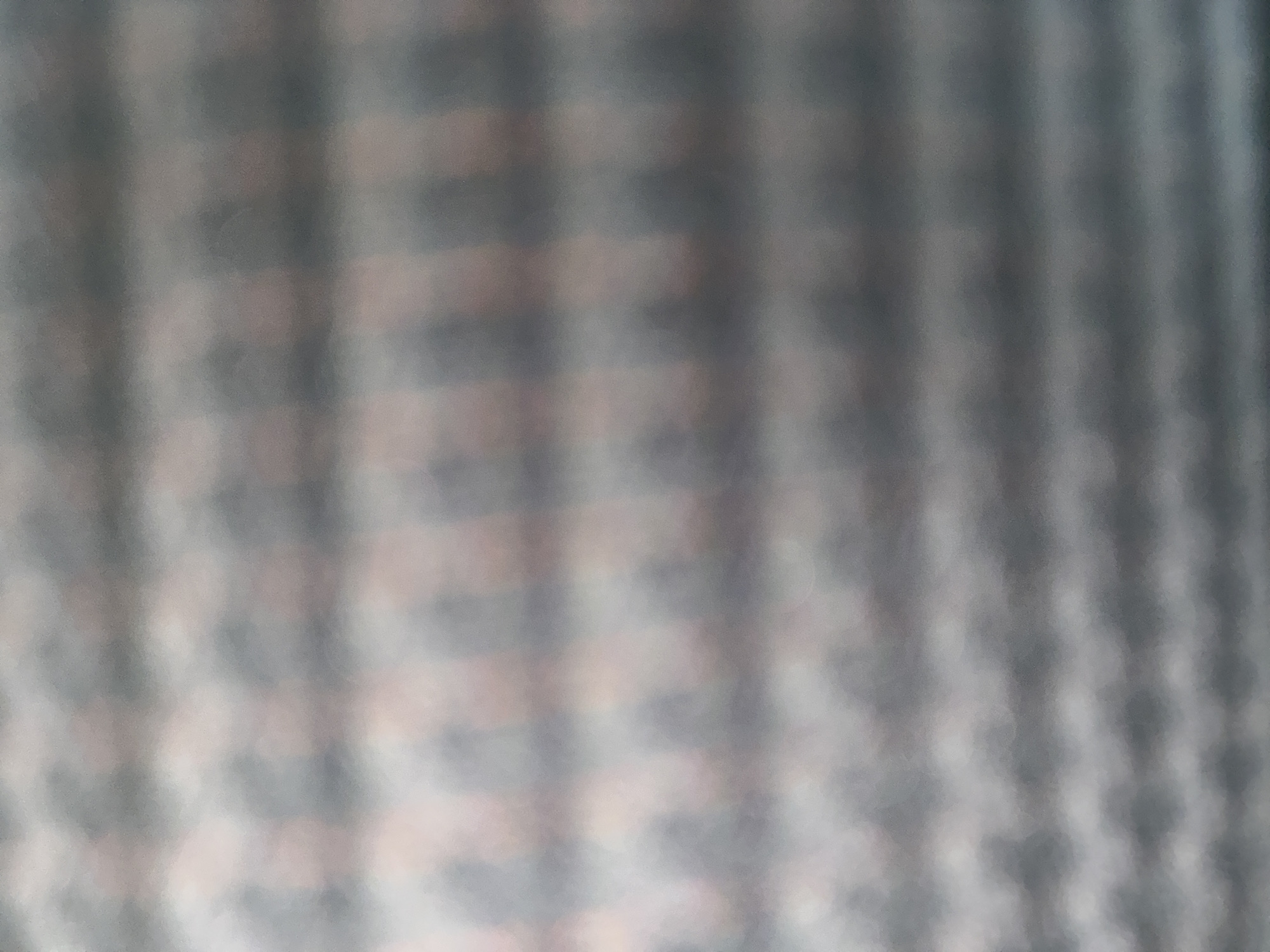 The image depicts a blurred, abstract pattern of horizontal bands with subtle color variations. The colors appear to be muted shades of gray, pink, and off-white, creating a soft, textured effect. The pattern suggests a repeating geometric design, possibly a fabric or a textured surface. There are no discernible people, objects, actions, or interactions visible due to the extreme blurriness. The location is not identifiable within the image, and therefore, it cannot be placed in Venice, United States.