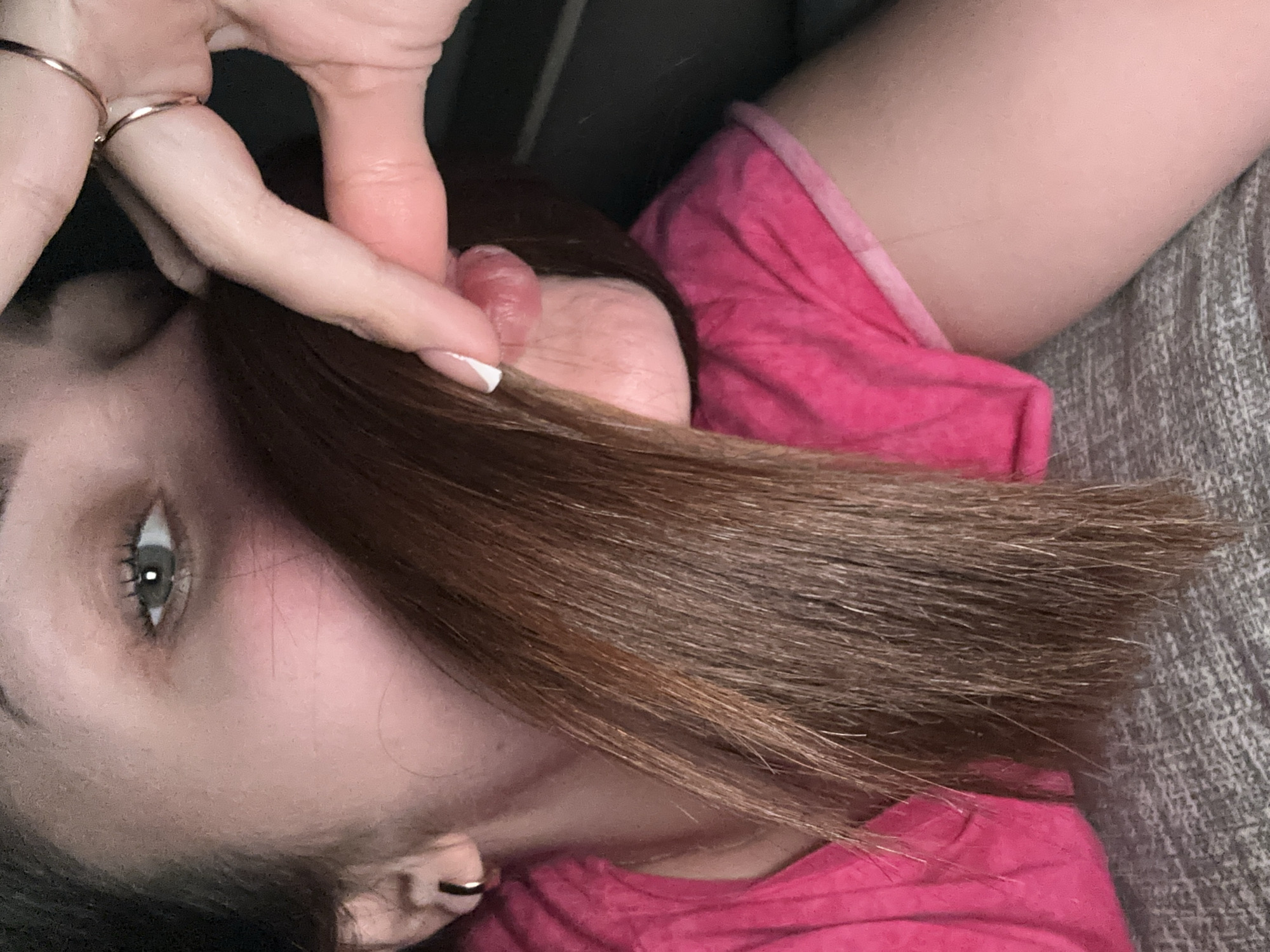 A close-up, angled view of a woman with light skin and brown hair. Her left eye is visible, along with part of her face and ear. She is wearing a pink shirt and is lying on a textured surface. Her hand is near her face, with two rings visible on her fingers. The background is blurred. There is no information about the location being in Chaikovsky, Russia.