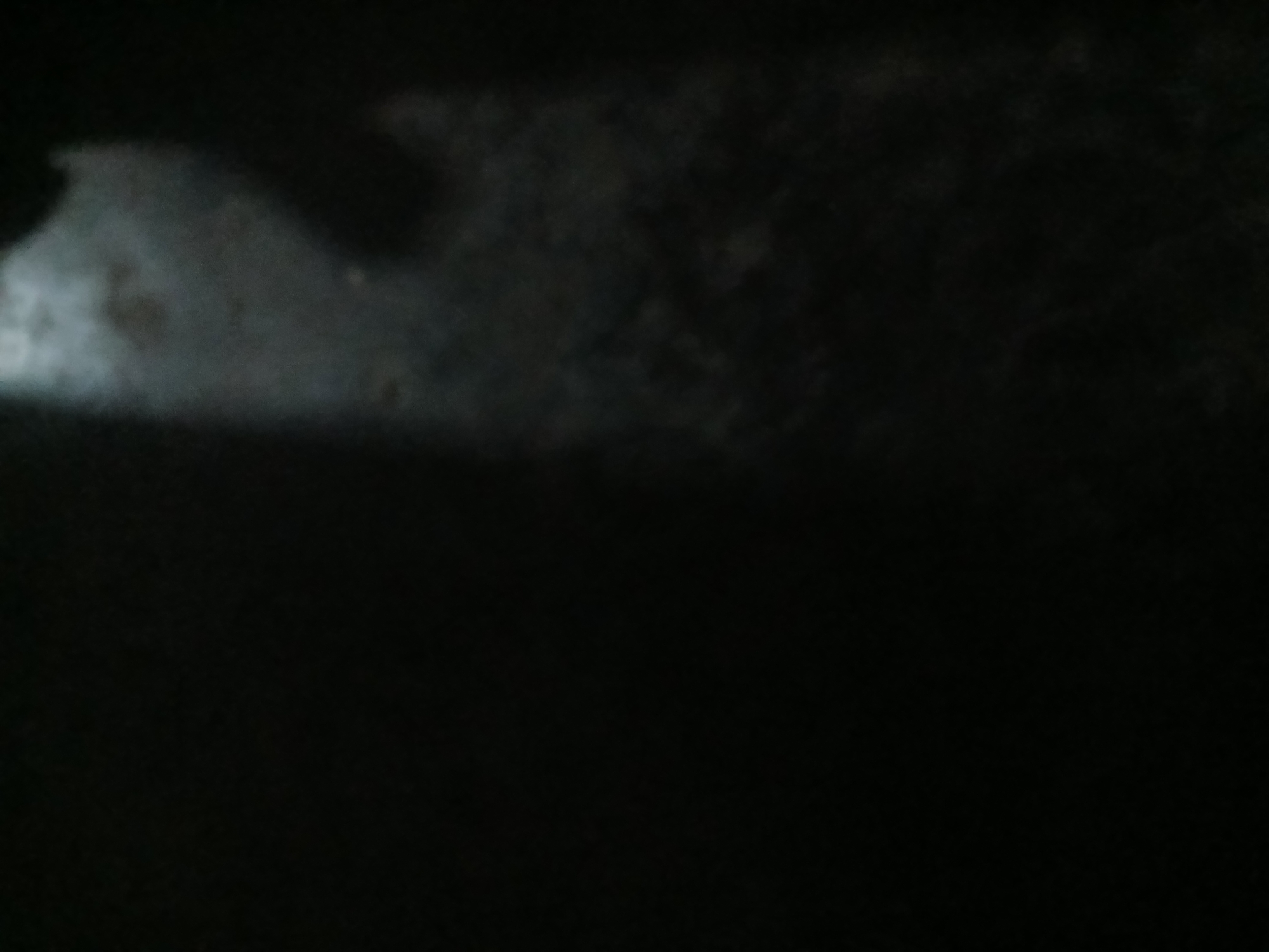 The image depicts a dimly lit, possibly rural, outdoor environment. A prominent diagonal beam of light cuts across a dark, textured surface, suggesting a light source from an elevated position. The ground appears to be uneven and possibly made of dirt or gravel, with scattered debris or foliage. The overall impression is one of low light conditions, potentially dusk or nighttime, with minimal discernible features of urban infrastructure. The reference to Kademangan Kulon, Indonesia, suggests a specific geographical context, but the visual information within the image does not directly confirm or deny this location.