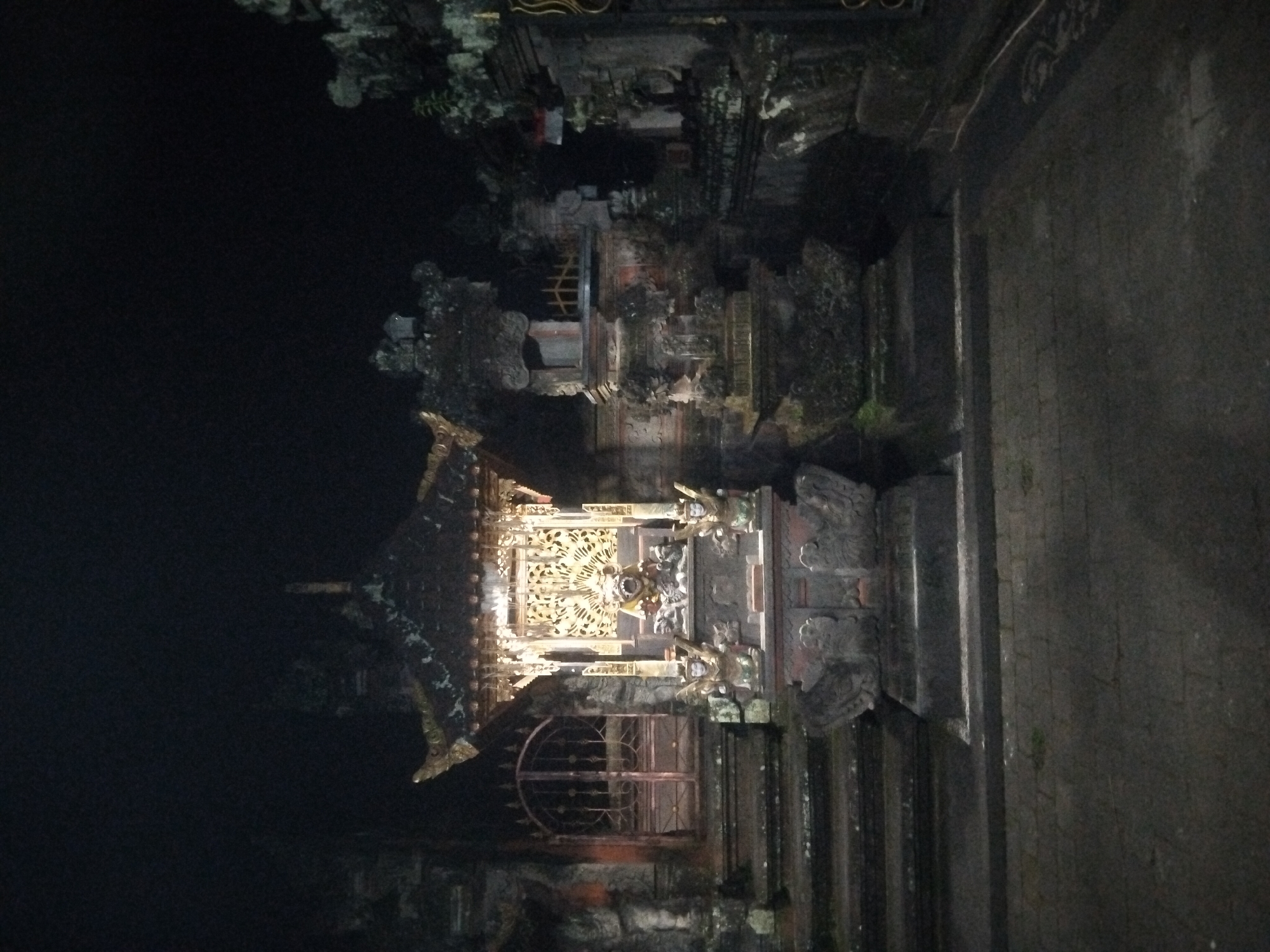 The image shows a temple at night. The temple is made of stone and has intricate carvings. The building is lit up with lights, which makes the carvings stand out. The overall environment is dark. The exact location is not clear.