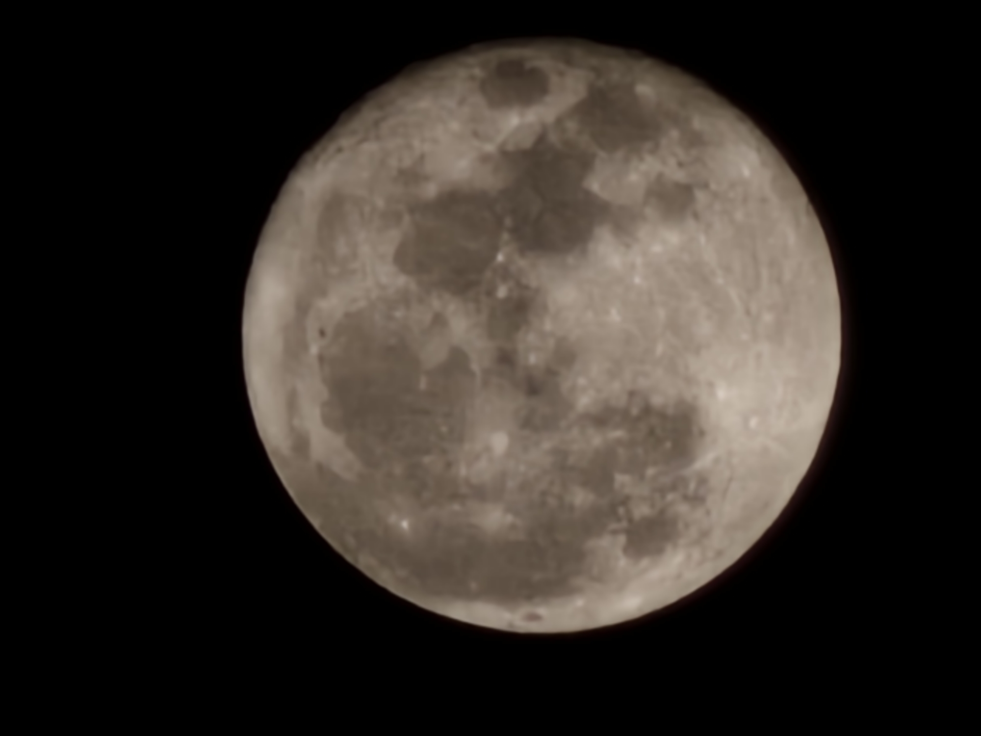 A full moon is centered in the right half of the frame against a black background. The moon's surface shows craters and varying shades of gray.
There is no indication of the location, any people, or any subjects or actions visible in this image.
