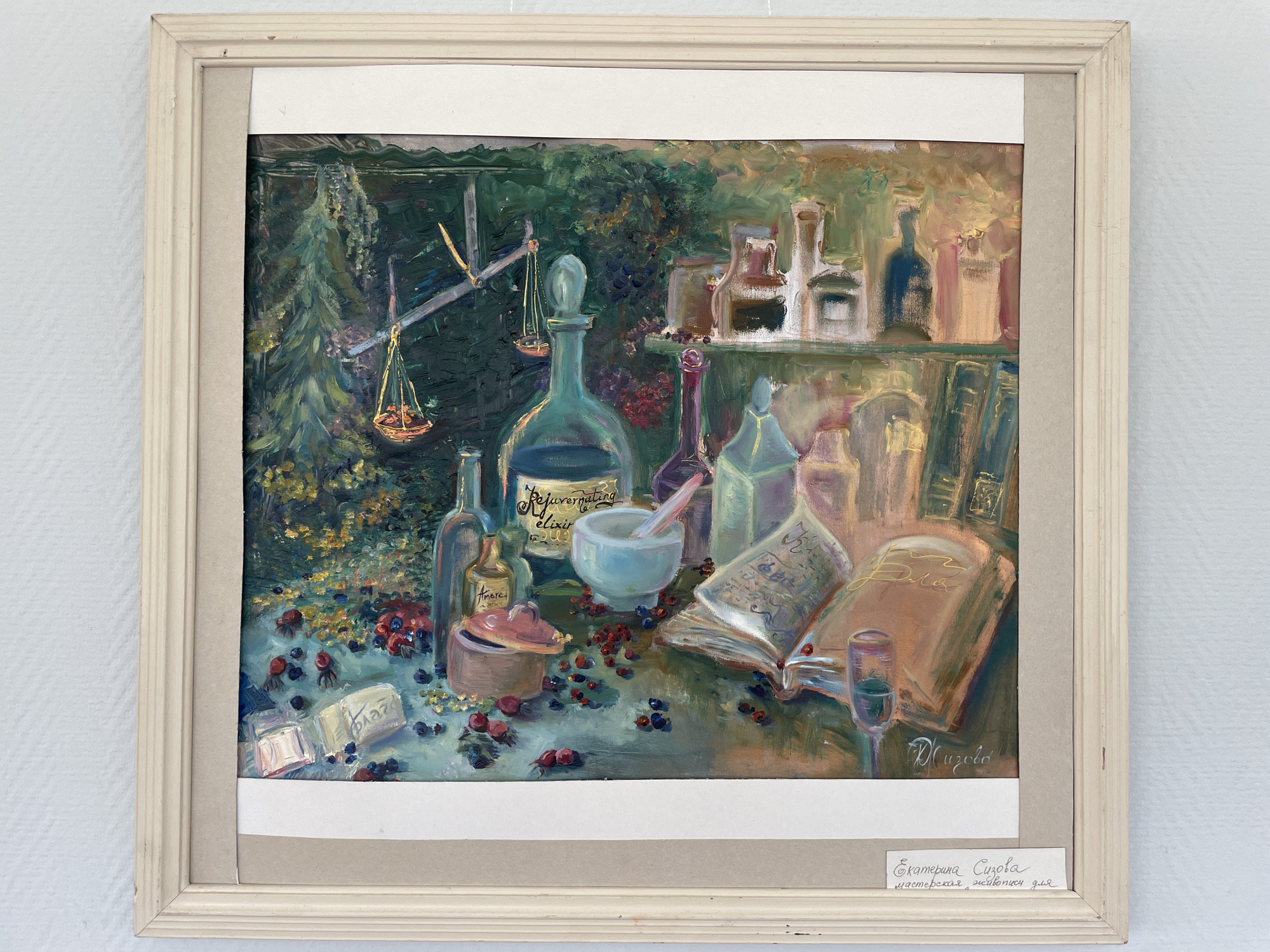 This is a framed oil painting depicting a still life. The subjects include various glass bottles and jars, some filled with dark liquids, arranged on a shelf and a table. A mortar and pestle, a small lidded pot, and scattered berries are also visible. Two open books are placed on the table, one with handwritten text. A small glass with a dark liquid sits next to the books. In the background, there's a dense green foliage, suggesting an outdoor or garden setting, and a wooden structure with hanging scales.
The overall impression is that of an apothecary or a witch's workshop, evoking a sense of mystery and ancient practices. The lighting suggests it might be indoors during the day, or perhaps twilight. There are no people visible.
Visible text includes:
- On one of the bottles in the background: "Rejuvenating elixir" (in script).
- On a smaller bottle in the foreground: "Amore" and "Elixir" (in script).
- A signature in the bottom right of the painting: "Е. Сизова" (E. Sizova).
- A label at the bottom of the frame reads: "Екатерина Сизова мастерская живописи для" (Ekaterina Sizova, painting workshop for).