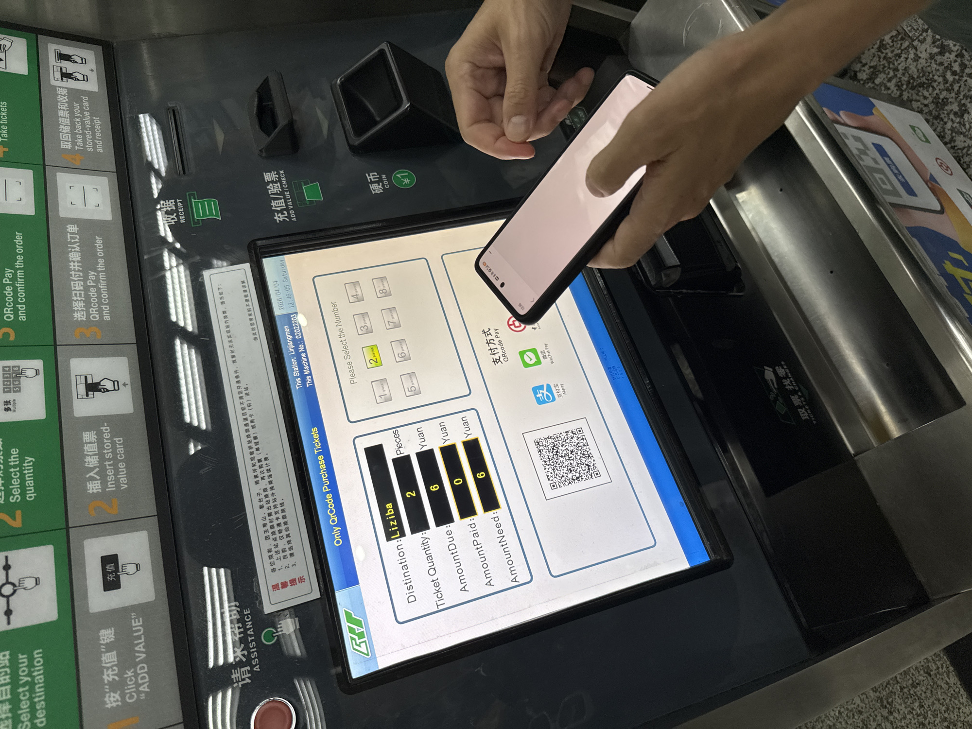 The image shows a person using a smartphone to purchase tickets at a metro station ticket vending machine in the Yuzhong District, China. The vending machine screen displays options in Chinese, and the person is using a QR code payment method. The screen indicates a destination of "Liziba," a quantity of two tickets, an amount due of six Yuan, an amount paid of zero Yuan, and an amount needed of six Yuan. The vending machine provides options for ticket purchases, adding value to stored-value cards, and assistance. The machine also includes slots for coins and dispensing tickets. The time and date displayed on the screen are 12:46:05 on Saturday, April 4, 2026. A sticker on the side of the machine shows instructions on how to purchase tickets. The smartphone is being held over the machine, presumably to scan the QR code displayed on the vending machine's screen.