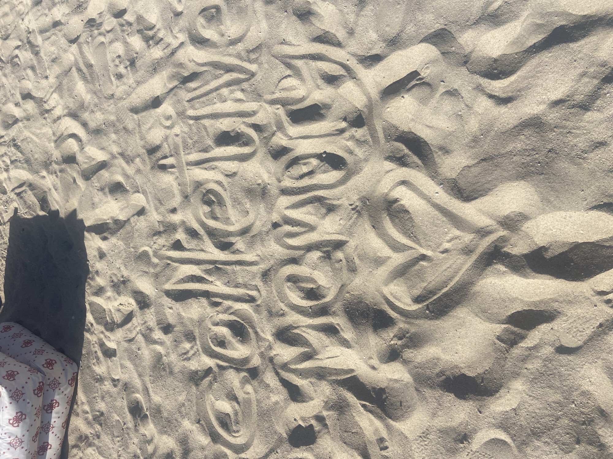 The image shows writing in the sand, spelling "Only you" with a heart drawing beside it. The location is likely a beach, possibly in Dubai, United Arab Emirates. The sand is light in color and textured. Part of a patterned object is visible in the lower left corner. No people are visible.