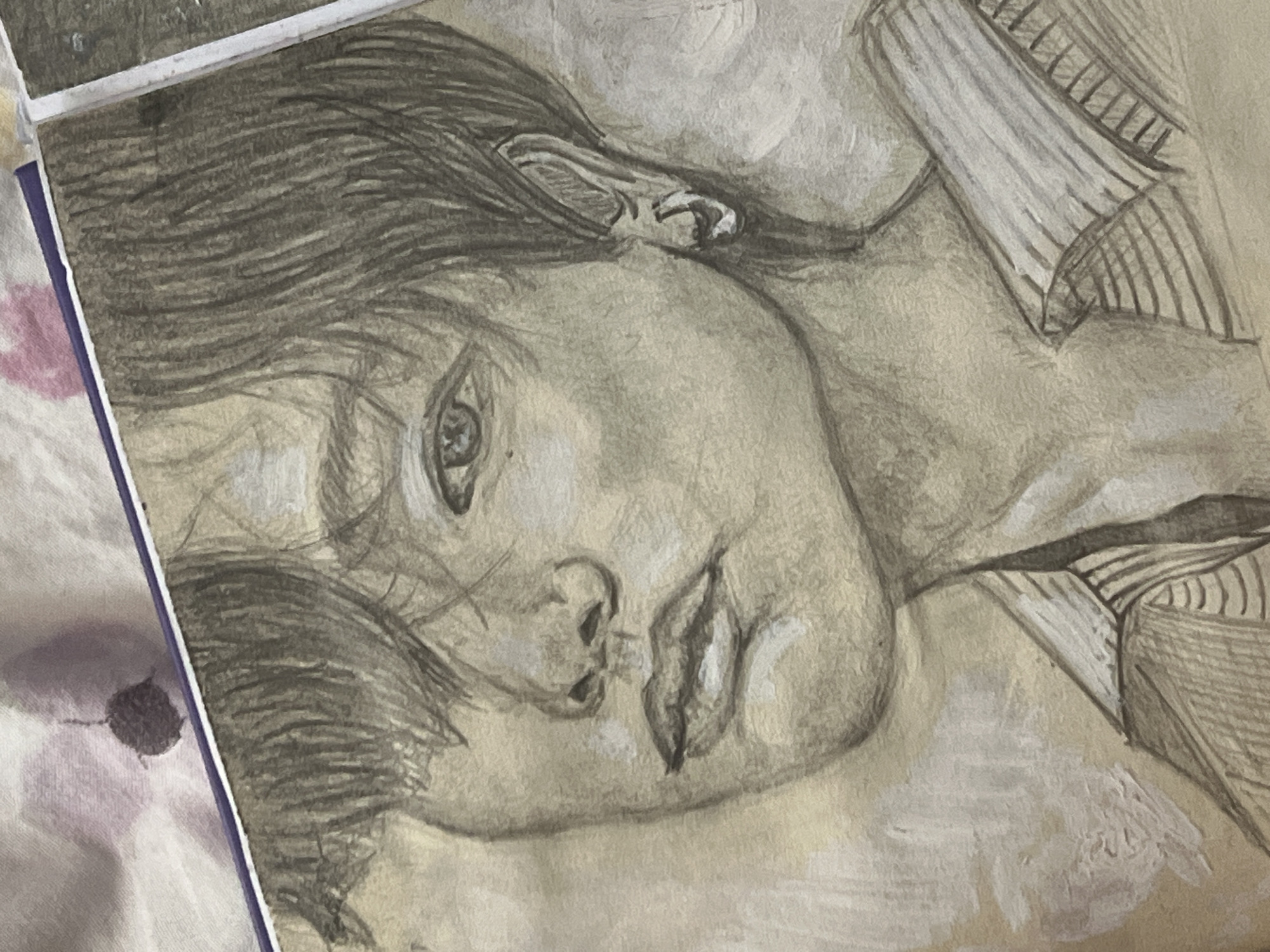 The image is a close-up, medium shot of a graphite and charcoal portrait of a young person. The portrait is rendered on paper that appears to have a light brown, textured surface, with some areas of white paint or gesso applied abstractly in the background. The subject is depicted from the shoulders up, facing slightly to the left. They have dark, tousled hair that partially obscures one eye. Their features are delicately drawn, with attention to the eyes, nose, lips, and ear. The subject is wearing a collared shirt with horizontal stripes. The overall tone of the portrait is somber and expressive. There are no discernible elements in the image that would indicate a specific location in the city of Shymkent, Kazakhstan, or any other urban environment.