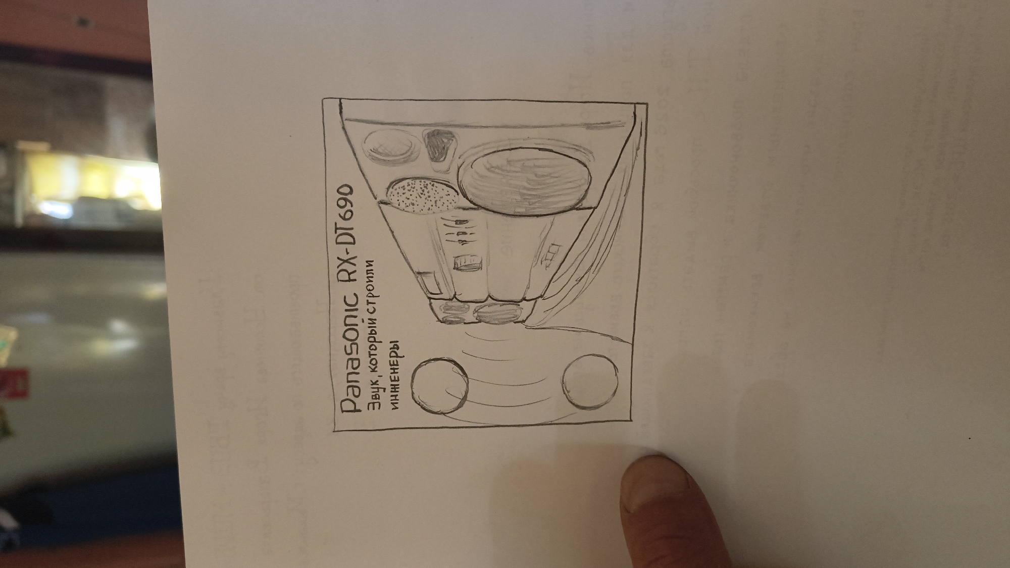A pencil sketch on paper depicts a Panasonic RX-DT690 boombox with the Russian text "Звук, который строили инженеры" (Sound that engineers built) below it. The boombox is shown with sound waves emanating from its speakers, represented by concentric circles. The sketch is framed by a simple border. The paper itself appears to be part of a larger document, with faint, printed text visible in the background. The lower-left corner of the image shows a portion of a person's thumb and index finger. The scene is a close-up, isolated view of the drawing. There is no indication of the city of Mikhaylovka, Russia, or any other geographical context within the image itself.