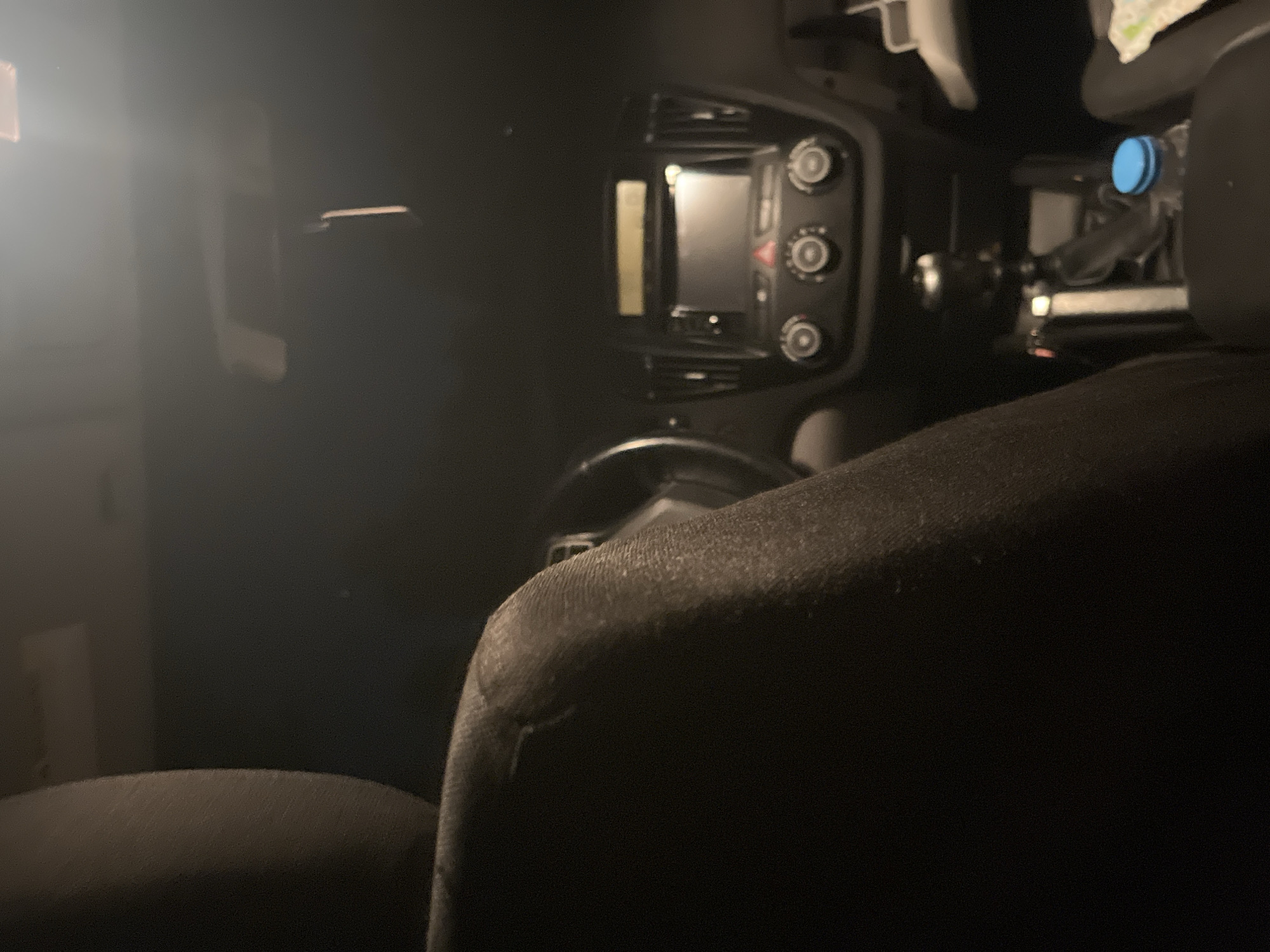 The image shows the interior of a car at night. The dashboard is visible, including the radio and climate controls. A water bottle with a blue cap sits in the center console. The front passenger seat is in the foreground. The location is unknown and there is nothing to indicate it's in Marulevo, Bulgaria. No people are visible.