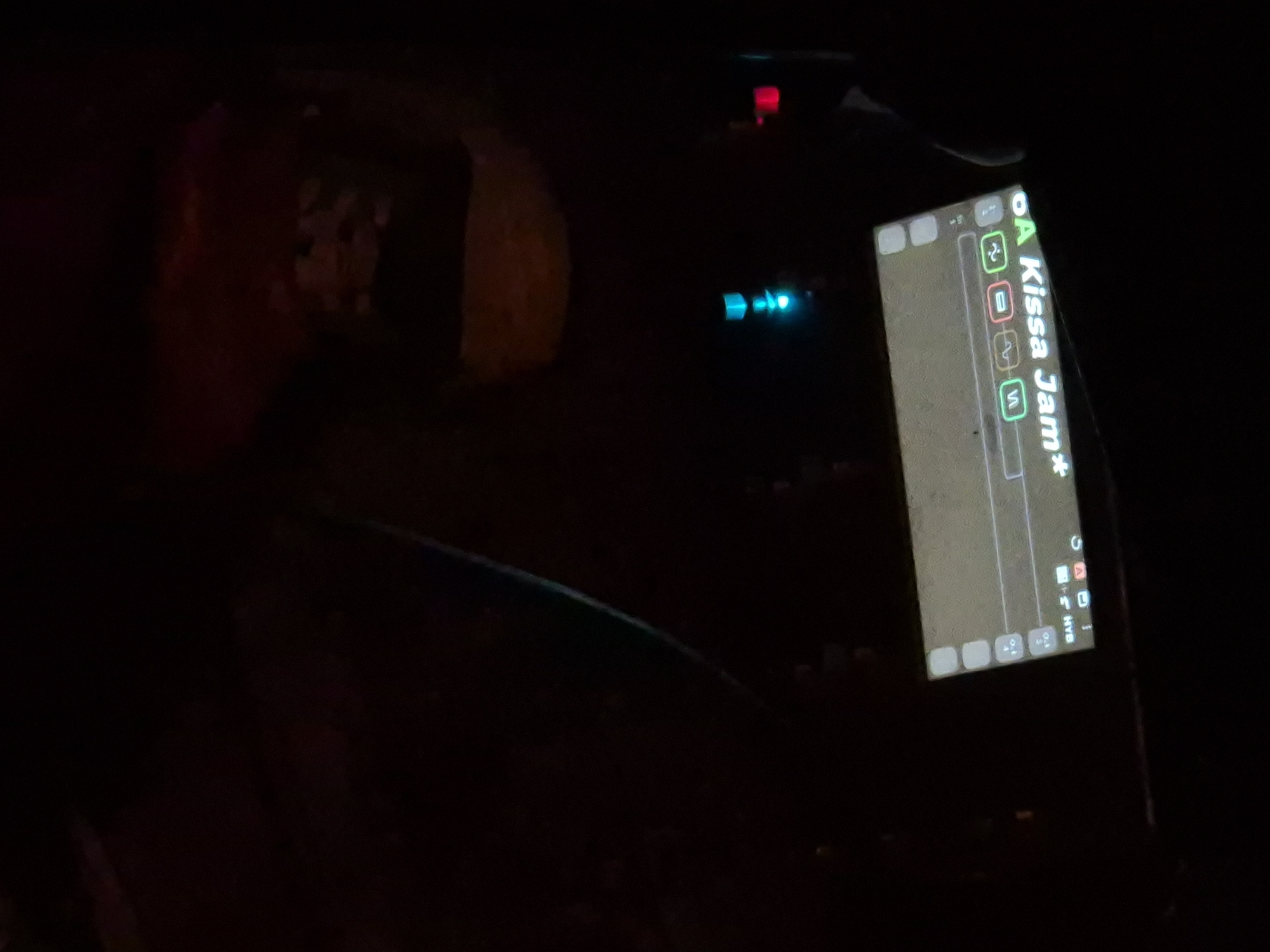 The image shows the interior of a car at night. The infotainment system displays a screen with the text "Kissa Jam*". The steering wheel is visible in the lower part of the frame. Other lights and reflections suggest the scene is inside a moving car. The location in Tel-Aviv, Israel is not confirmed.