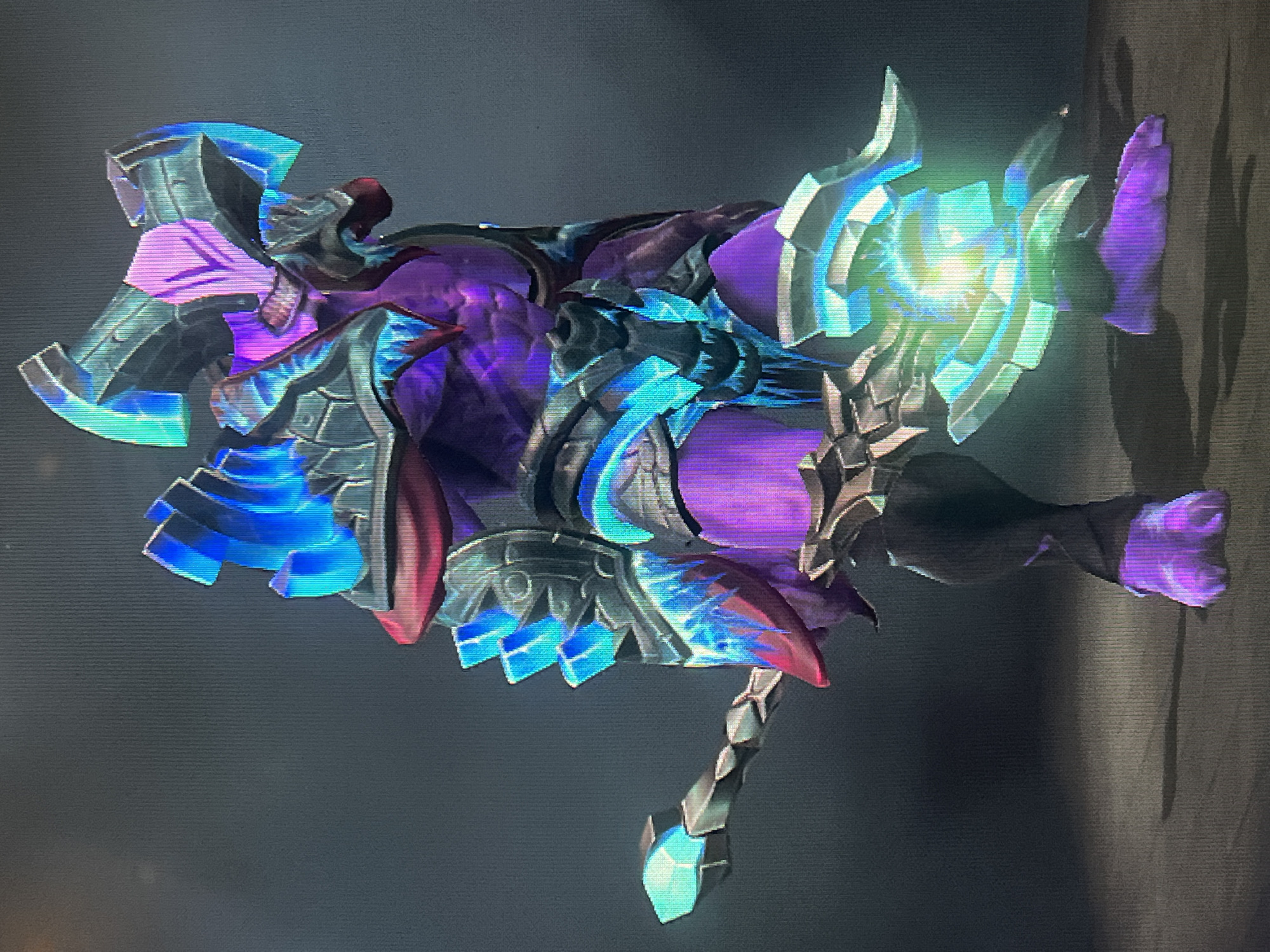 The image shows a digital rendering of a fantasy creature, possibly from a video game. The creature is primarily purple with metallic armor adorned with glowing blue and green crystalline elements. It has a menacing, reptilian head and appears to be holding a staff or weapon. The background is a dark, plain gradient. There is no indication of any real-world location, including the city of Đà Nẵng, Vietnam.