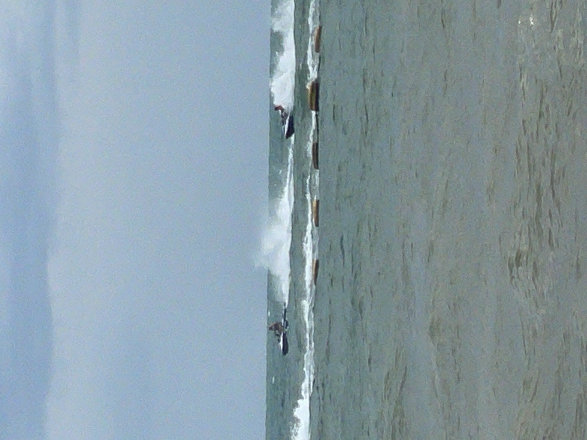 Two jet skis are seen racing on the choppy waters of the ocean under a cloudy sky, with one jet ski slightly ahead of the other. Both jet skis are creating wakes as they move. In the foreground, there are several yellow buoys floating on the surface of the water. The scene appears to be a recreational activity, possibly a competition, taking place in Pattaya City, Thailand, given the presence of the ocean and common water sports.