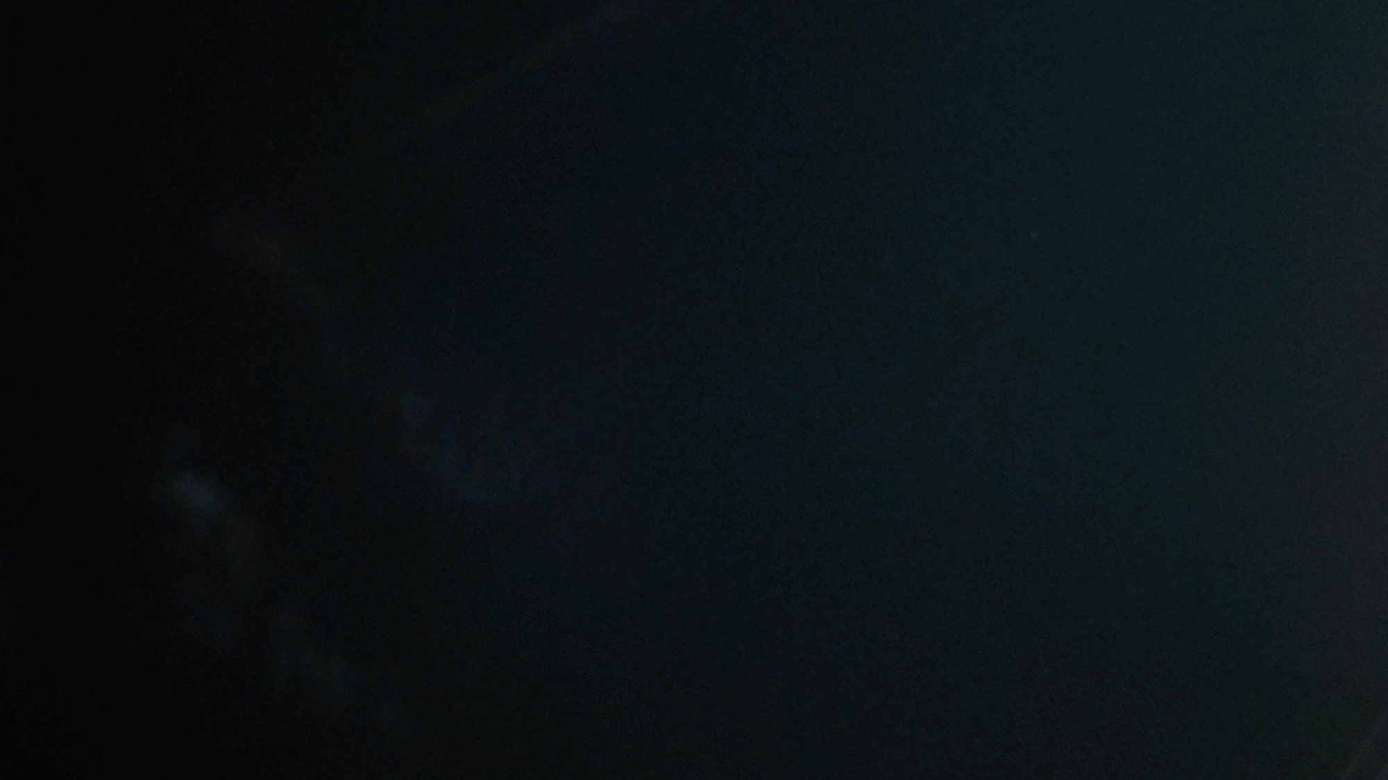 The image is a dark, almost black sky with a faint, possibly rainbow-like, arc visible in the upper right quadrant. The sky appears to have some subtle cloud formations or atmospheric phenomena. No objects, people, or urban elements are discernible, indicating the image was likely taken from an open area, possibly away from significant light pollution, allowing for a view of the night sky. The location in Abovyan, Armenia, suggests this is a view of the sky above that city.