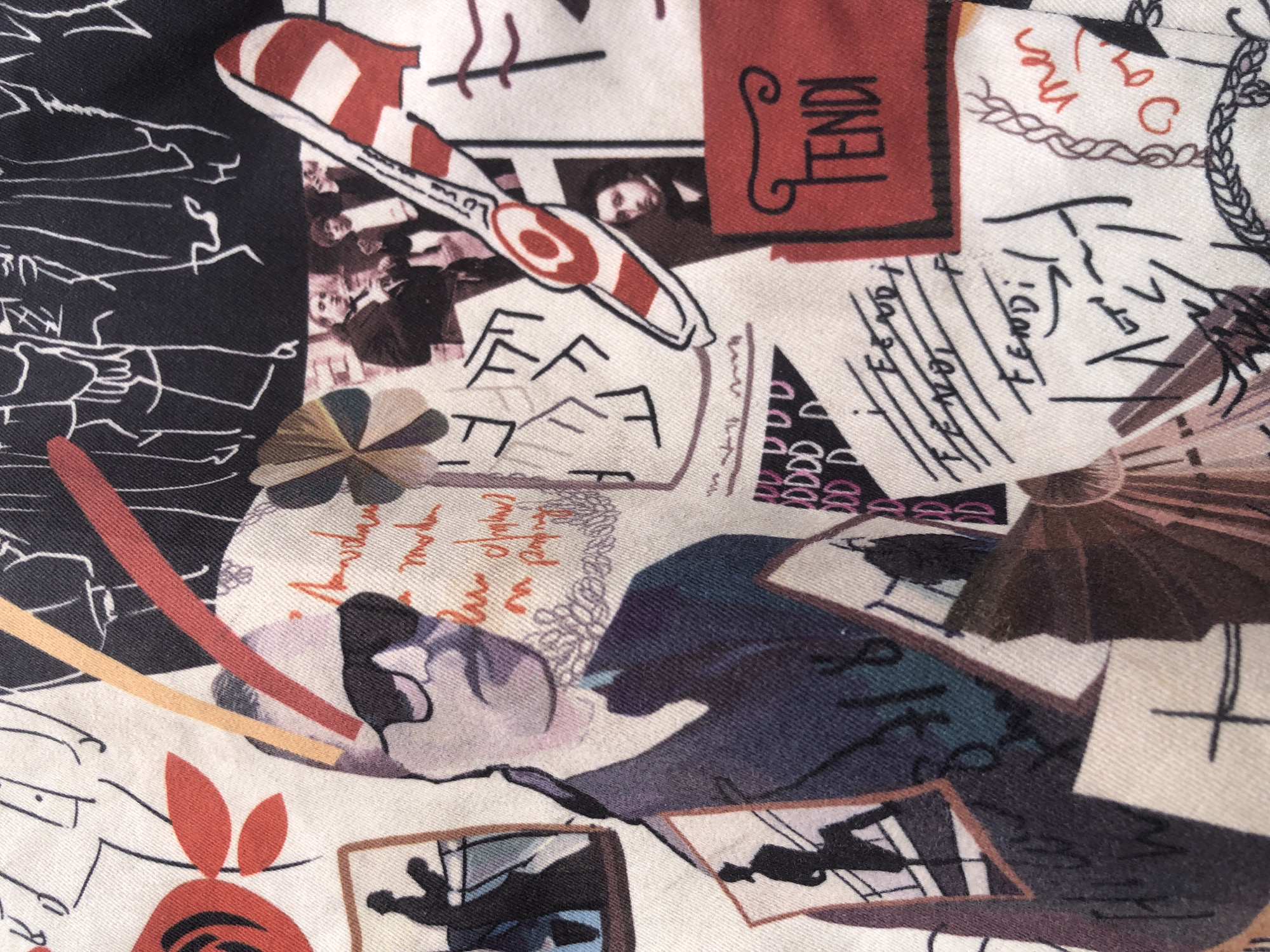 The image is a close-up of a fabric print with a collage of illustrations and text. There are stylized drawings of people, some appearing to be fashion sketches. A prominent element is a cartoonish depiction of a man wearing sunglasses and a suit. Text elements include handwritten-style words like "FENDI" multiple times, and other illegible scribbles and symbols. There are also graphic elements such as stripes and abstract shapes. The overall aesthetic is artistic and resembles a designer print. The image does not contain any information about the city of Ado, Nigeria, nor does it depict any recognizable urban environment or specific scene that can be localized. Therefore, I cannot provide details about the location in Ado, Nigeria.