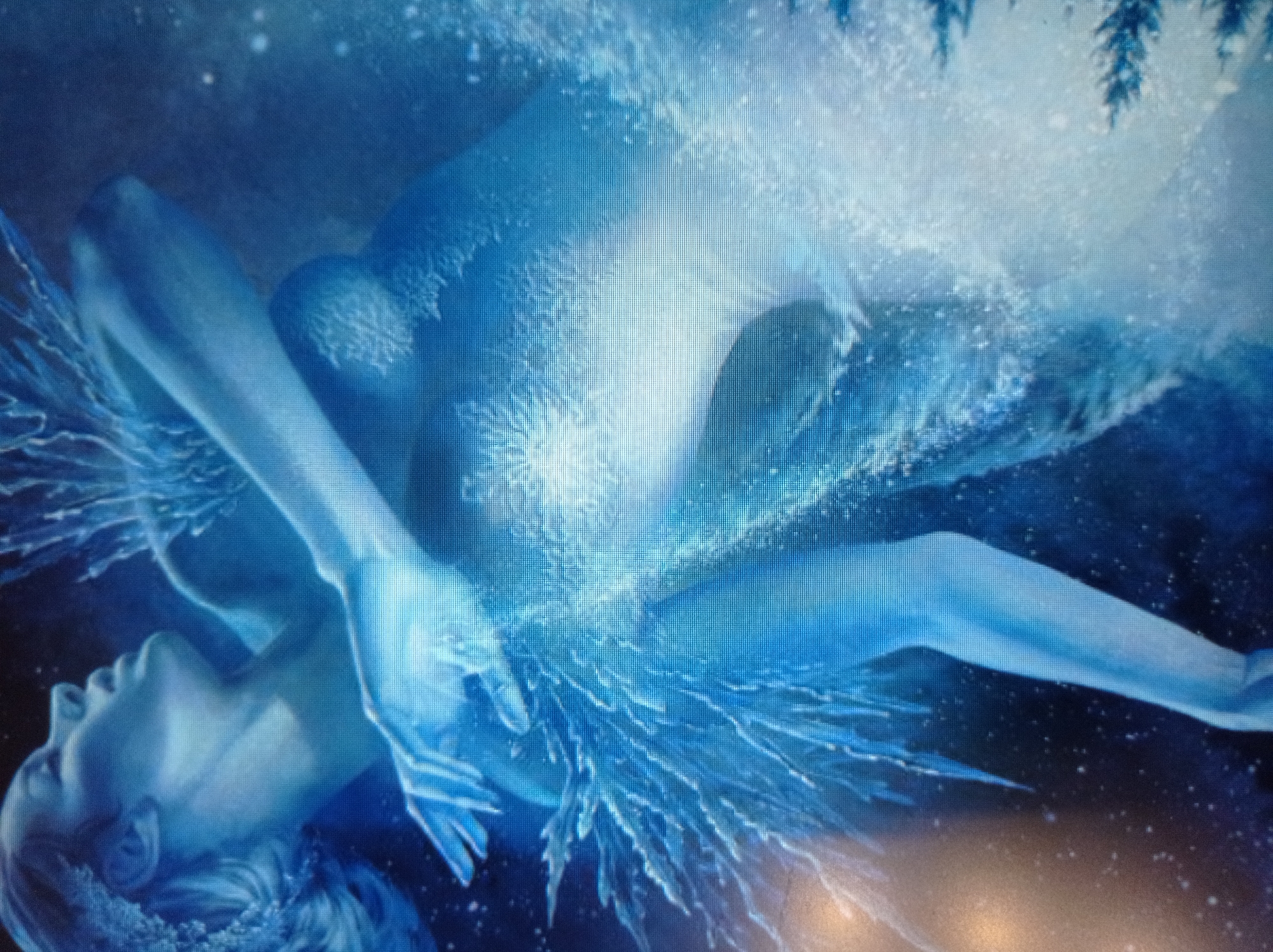 The image shows a close-up, digital rendering of a female figure composed of ice or frost. She is depicted in profile, facing to the right, with her hair styled in an icy crown. Her body is partially obscured by swirling, frozen elements that resemble shards of ice or snow. Her arms are raised and posed as if in motion, with icy tendrils extending from her shoulders and arms. The background is dark, with small white specks that could represent snow or stars. In the lower portion of the image, the silhouettes of evergreen trees are visible, suggesting a winter forest setting. The overall tone is ethereal and cold, with blues and whites dominating the color palette. The image does not depict any location in the city of Mukachevo, Ukraine.