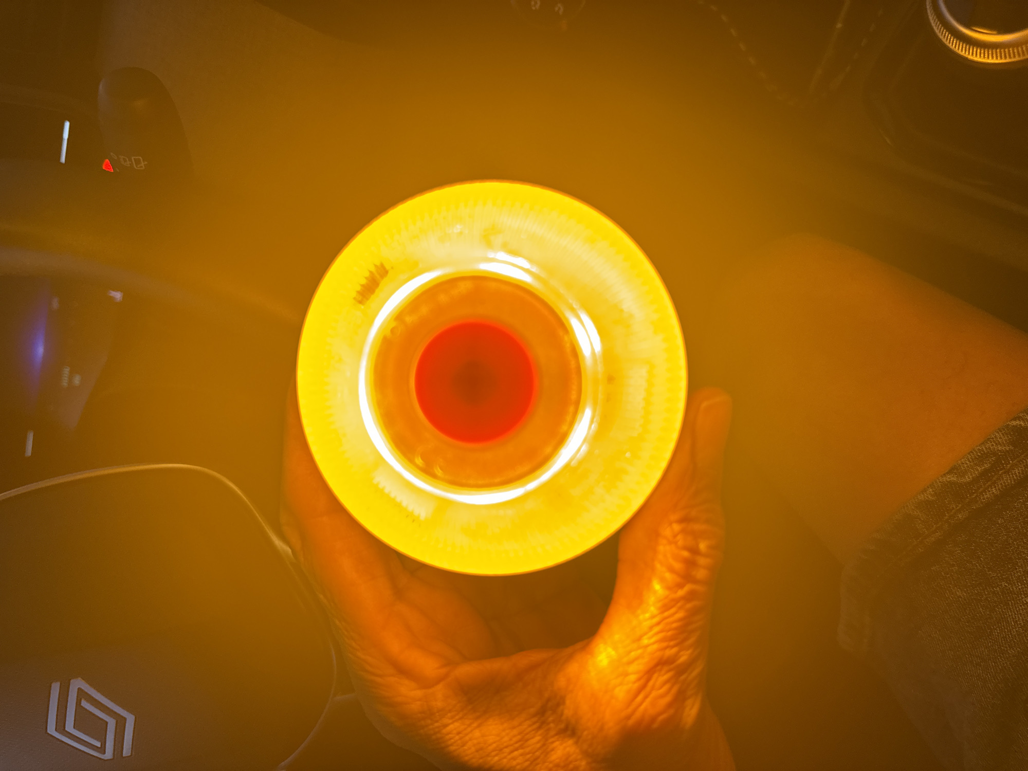 In a dimly lit interior, a person's hand holds a round object emitting a bright yellow and red light. The object appears to be some kind of illuminated device, possibly a lantern or a light fixture. The background is dark and indistinct, suggesting an indoor setting. The image does not provide any information about the city of Murcia, Spain, nor any specific context to place it within that location. The scene is focused on the illuminated object and the hand holding it, with the surroundings out of focus.