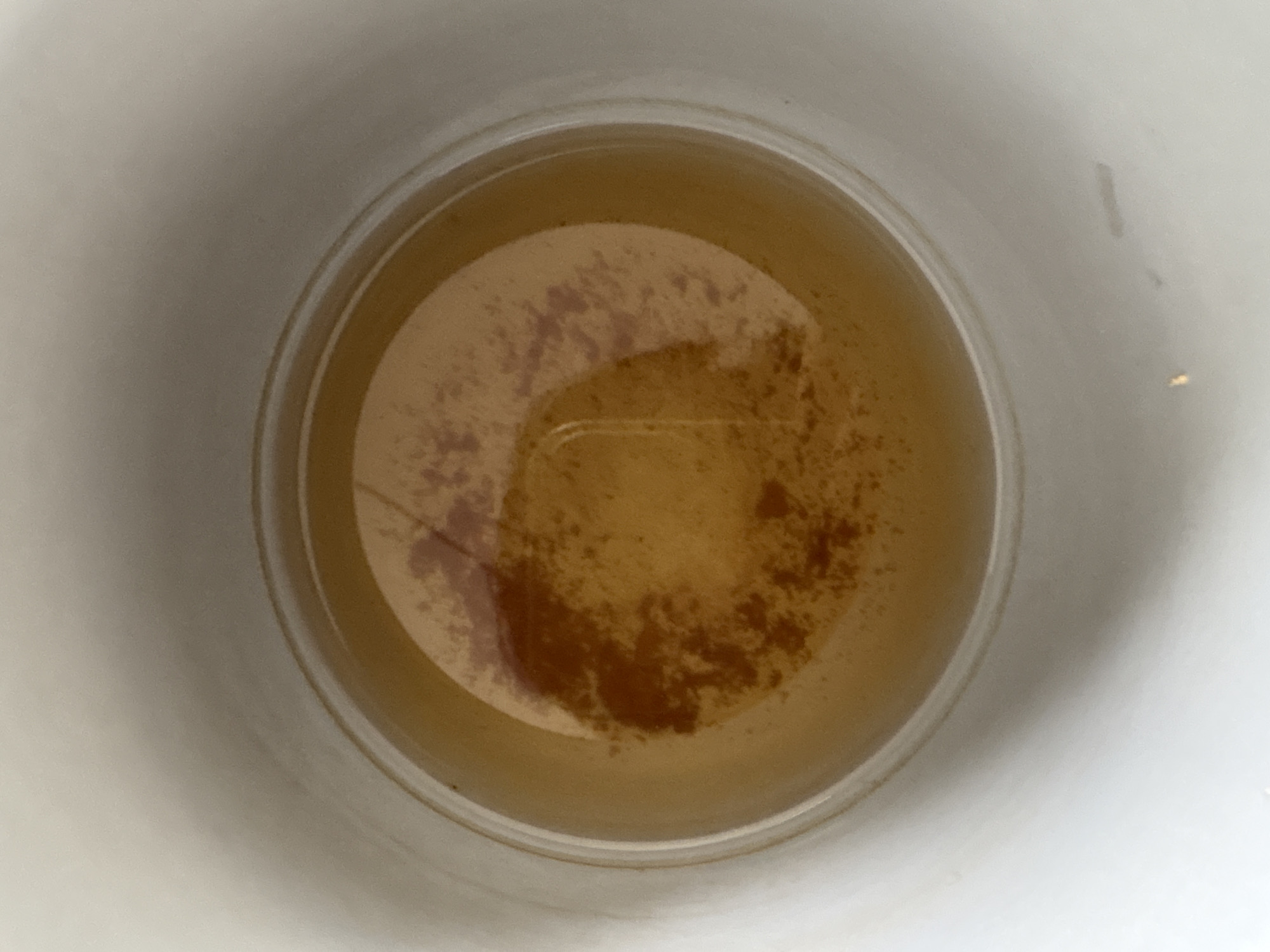 A top-down view shows a white cup filled with a light brown liquid containing dark brown sediment. The liquid appears to be tea or coffee grounds. The cup is plain and white. There are no people visible. The location of Ембаево, Russia is not discernible from the visual information.