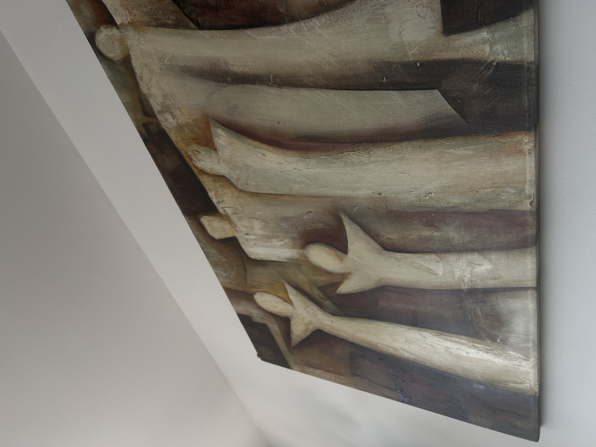 The image depicts an abstract painting hanging on a white wall. The painting features earth tones like brown, beige, and white, with textured brushstrokes and indistinct shapes. Some of the shapes vaguely resemble human figures with outstretched arms. The painting is hung on an angle, suggesting it's in an interior space with a slanted ceiling. The image does not contain information about the location being Mexico City, Mexico.