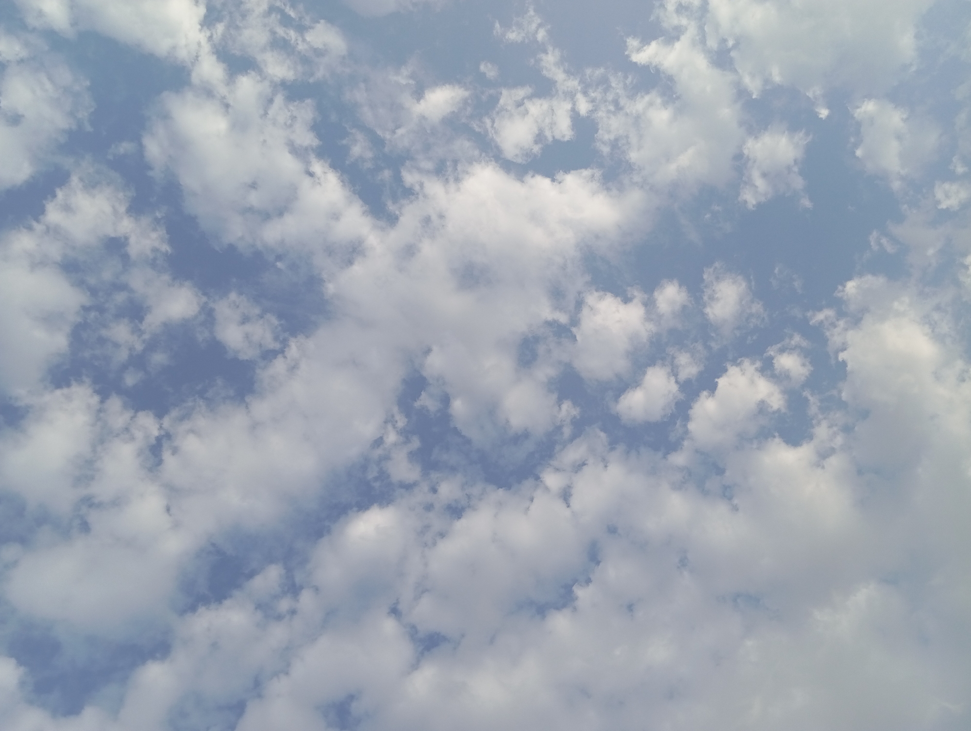 The image is a photograph of a sky with scattered clouds. The sky is a light blue color, and the clouds are white and puffy. The photograph is taken from a low angle, looking up at the sky. There are no people, animals, or man-made objects visible in the image. The photograph does not provide any specific information about the location in the city of Şirvanlı, Azerbaijan, beyond the fact that it is an outdoor scene.