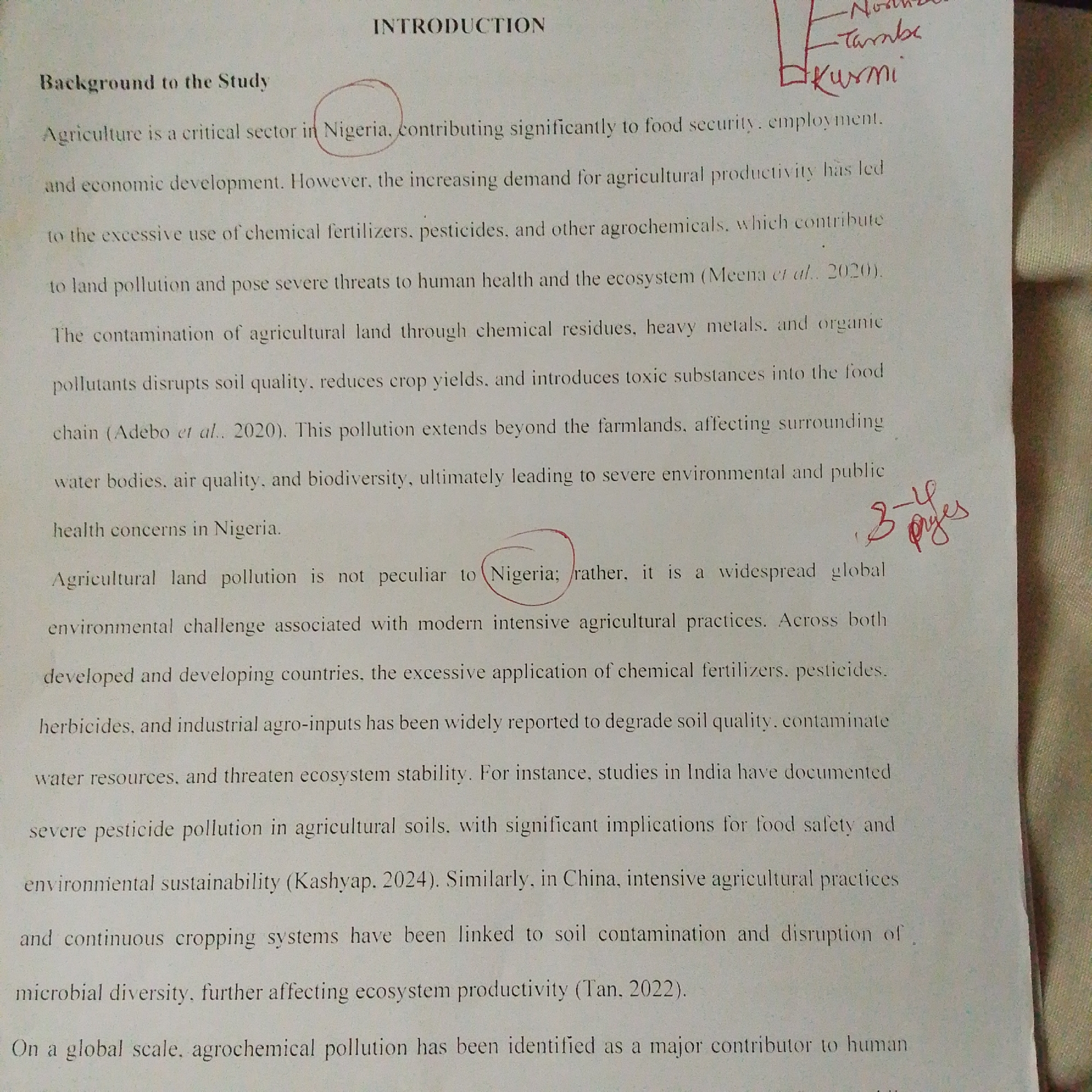 The image shows a close-up view of a document with text. The document is titled "INTRODUCTION" and has a section labeled "Background to the Study". The text discusses agriculture in Nigeria, its contribution to food security and economic development, and the negative impacts of chemical fertilizers, pesticides, and other agrochemicals. It mentions land pollution, threats to human health and the ecosystem, and contamination of soil, water, and air. The text also refers to studies conducted in India and China regarding agricultural pollution and its effects on environmental sustainability and ecosystem productivity. There is a handwritten annotation on the top right corner of the document which appears to be a name or a label. Additionally, there are two red circles drawn around the word "Nigeria" in the text, and a red annotation on the right side of the page with some numbers and words, possibly indicating page references. The background of the image appears to be a textured surface, possibly fabric. The image does not contain any information about the city of Jalingo, Nigeria.