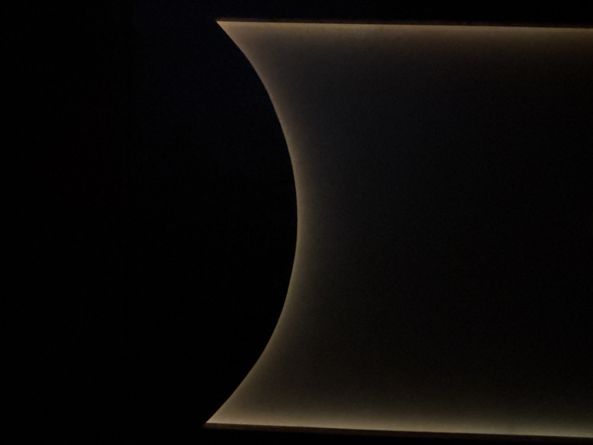 A dark, abstract interior view. The left side is completely black. On the right, an illuminated curved edge descends from the top and extends to the bottom of the frame. The top and bottom edges of this illuminated area are also straight, with a thin strip of light. The location in Plovdiv, Bulgaria is not discernible from the image.