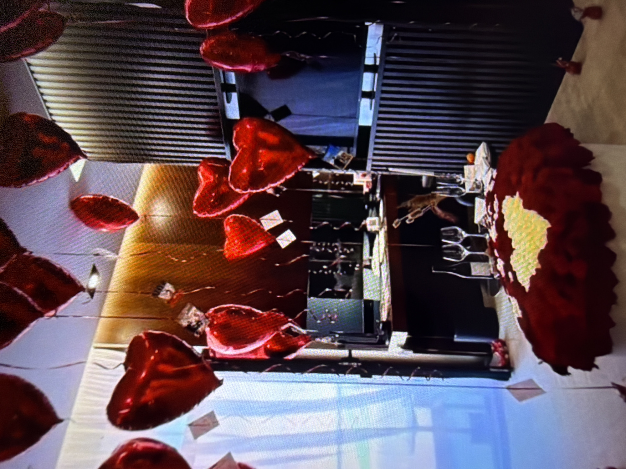 The media file shows a room decorated with many red heart-shaped balloons. Some of the balloons are clustered together, while others are scattered throughout the space. The balloons are of varying sizes and appear to be made of a shiny material, likely foil.
The setting appears to be an indoor space, possibly a room for an event or celebration. There are hints of furniture and decor, including what looks like a table with place settings, glasses, and a bottle. In the background, there are vertical blinds or slatted surfaces. The overall impression is festive and romantic, suggesting an occasion like Valentine's Day, an anniversary, or a wedding.
There is no clear indication of people being present in the image, nor is there any visible text. The lighting suggests it is daytime, but without external views, it's hard to determine the time of day or weather conditions. The location context provided is Beșalma, Moldova, which doesn't offer specific visual cues within the image itself. The focus is entirely on the abundant red heart balloons and the celebratory atmosphere they create.