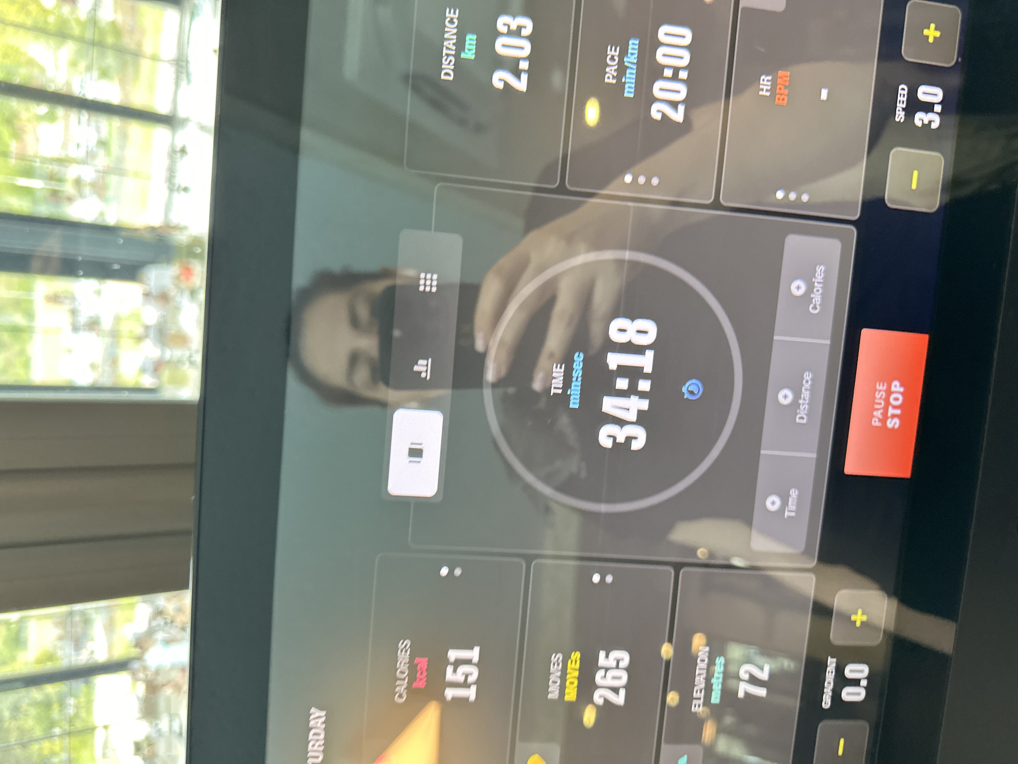 The image is a close-up shot of a treadmill console. The display shows various workout metrics including a distance of 2.03 km, a pace of 20:00 min/km, a time of 34:18, calories burned of 151 kcal, moves of 265, elevation of 72 metres, a gradient of 0.0, and a speed of 3.0. A "Pause/Stop" button is visible on the right. The treadmill screen reflects a person and an out-of-focus background with a window. The location or association with Kazanlak, Bulgaria is not discernible from the image.