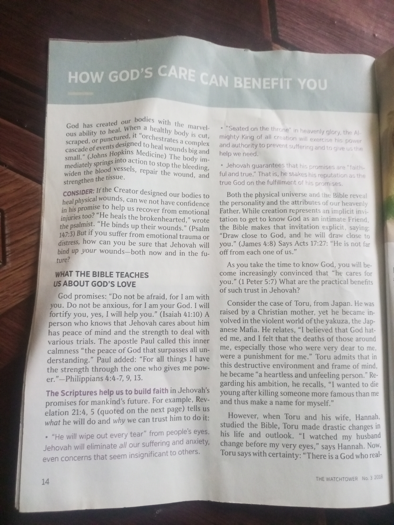 This media file is a photograph of an open magazine with text. The title of the article appears to be "HOW GOD'S CARE CAN BENEFIT YOU". The text discusses the healing capabilities of the human body, God's promises, and the importance of knowing God. It includes a personal anecdote about a man named Toru from Japan and his wife Hannah, and their spiritual journey. The magazine is identified as "THE WATCHTOWER No. 3 2018". The image is taken from an angle that shows a slight shadow on the right side, indicating indoor lighting. There are no discernible people, objects, or environmental elements other than the magazine itself. The provided location context of Jalingo, Nigeria, does not appear to be relevant to the visual content of the image.