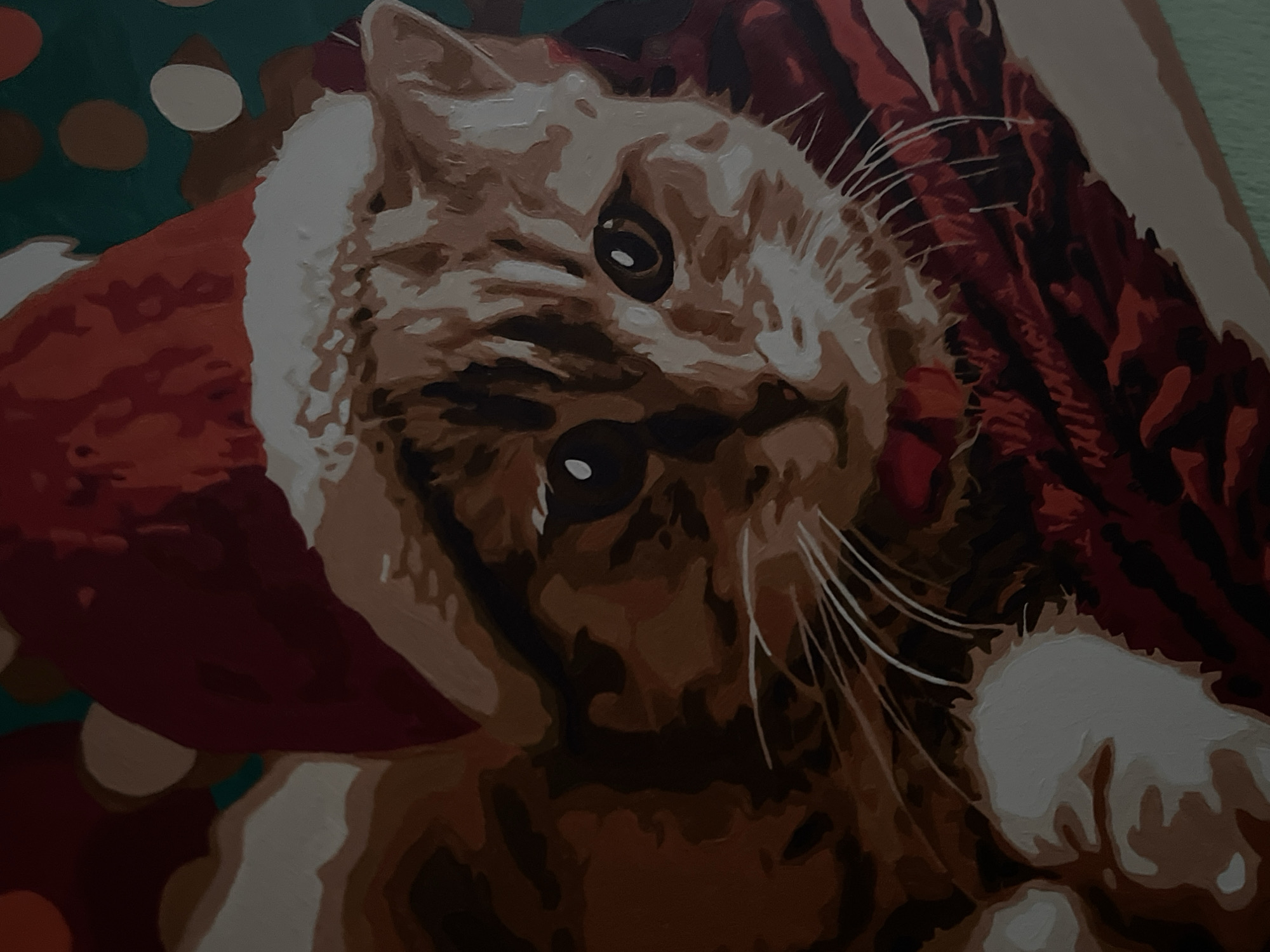 This is a close-up, painted image of a cat wearing a red Santa hat. The cat has tabby markings in shades of brown and cream, with large, dark eyes and white whiskers. The hat is red with a white trim and has a pom-pom that is partially obscured. The background is a mixture of dark green with blurred, circular bokeh lights in shades of white and brown, suggesting a festive or holiday setting. To the right of the cat, there's a textured red and dark brown area, possibly depicting fabric or a festive decoration. The painting style is somewhat abstract, with clearly defined areas of color rather than smooth blending. The overall mood is warm and festive. The location context is Lviv, Ukraine, but this information is not visually discernible from the image itself.