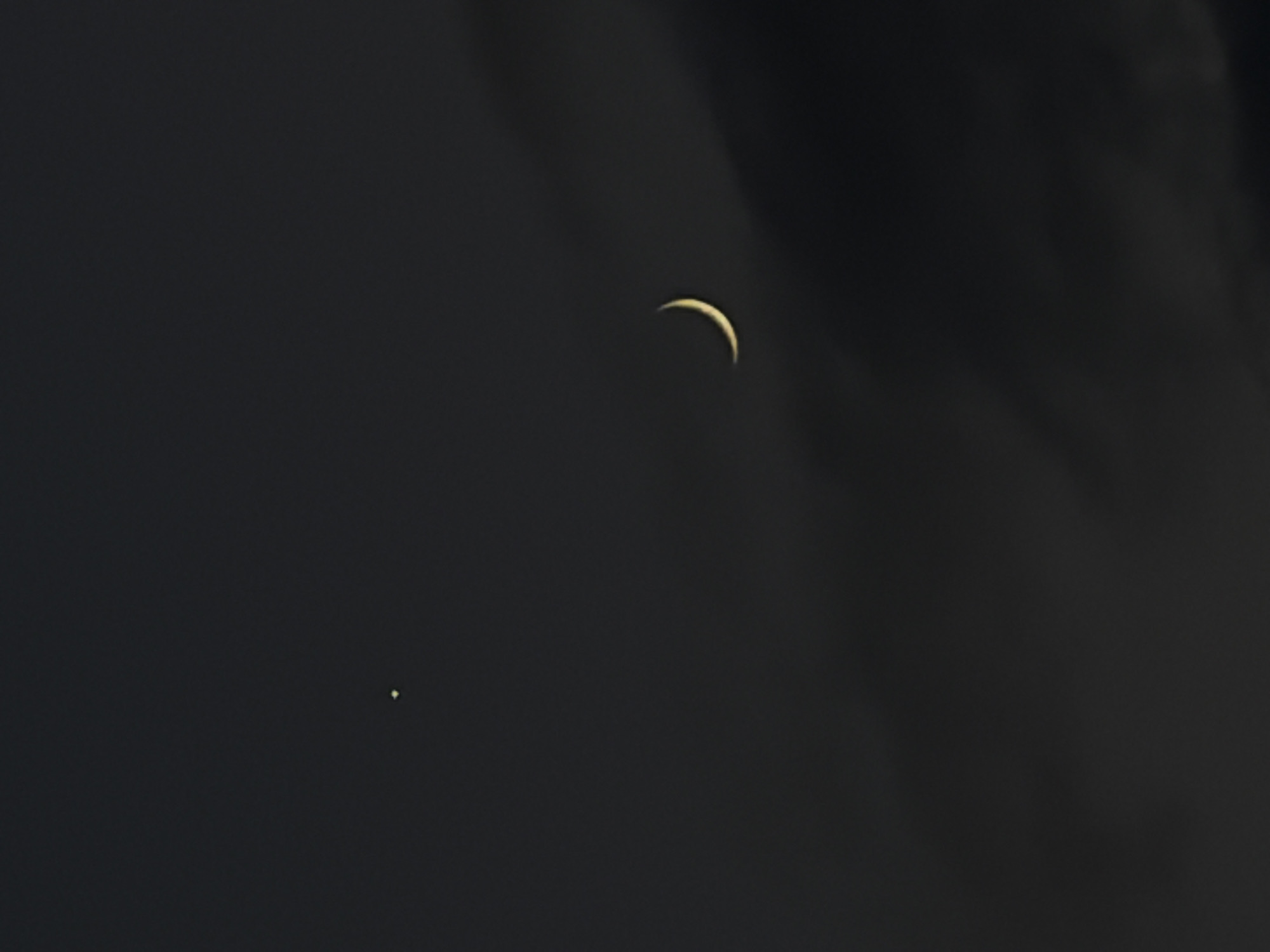 A crescent moon is visible in a dark, cloudy sky. To the left of the moon, a bright star is also visible. There are no people or objects in the image, nor are there any specific details about the location in Dongaron, Russia.