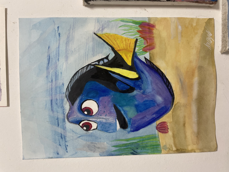 A watercolor painting of Dory from Finding Nemo. The fish is blue with black and yellow markings, with large, somewhat unsettling eyes. The background is divided, with the left side depicting a blue, watery scene, and the right side showing a brownish coral reef. The painting has a somewhat amateurish style. It's attached to a wall, possibly among other artworks.