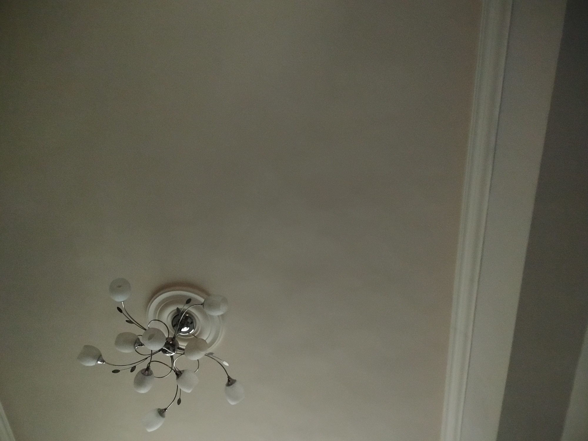 A photograph taken indoors shows a ceiling with white molding along the right edge and a chandelier hanging from the center of the ceiling. The chandelier has multiple light bulbs arranged in a circular pattern. The ceiling is a light, neutral color. This is likely a residential or commercial building. There is no evidence to identify the exact location in Yerevan, Armenia.