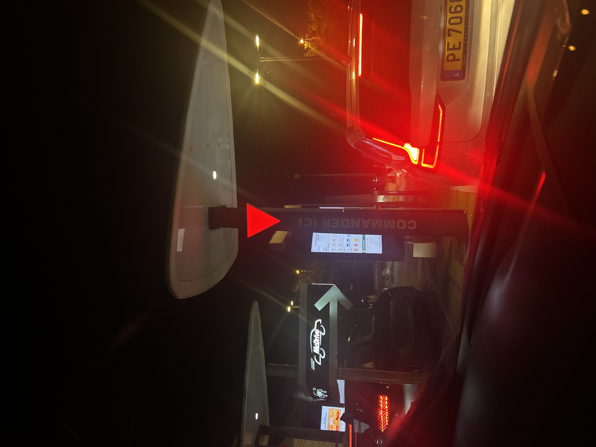 The image shows the McDonald's drive-thru in Noisy-le-Grand, France. A car is waiting to order at the "Commander ici" ordering point. The license plate of the car in front is PE 7068. The menu board is visible in the background.
