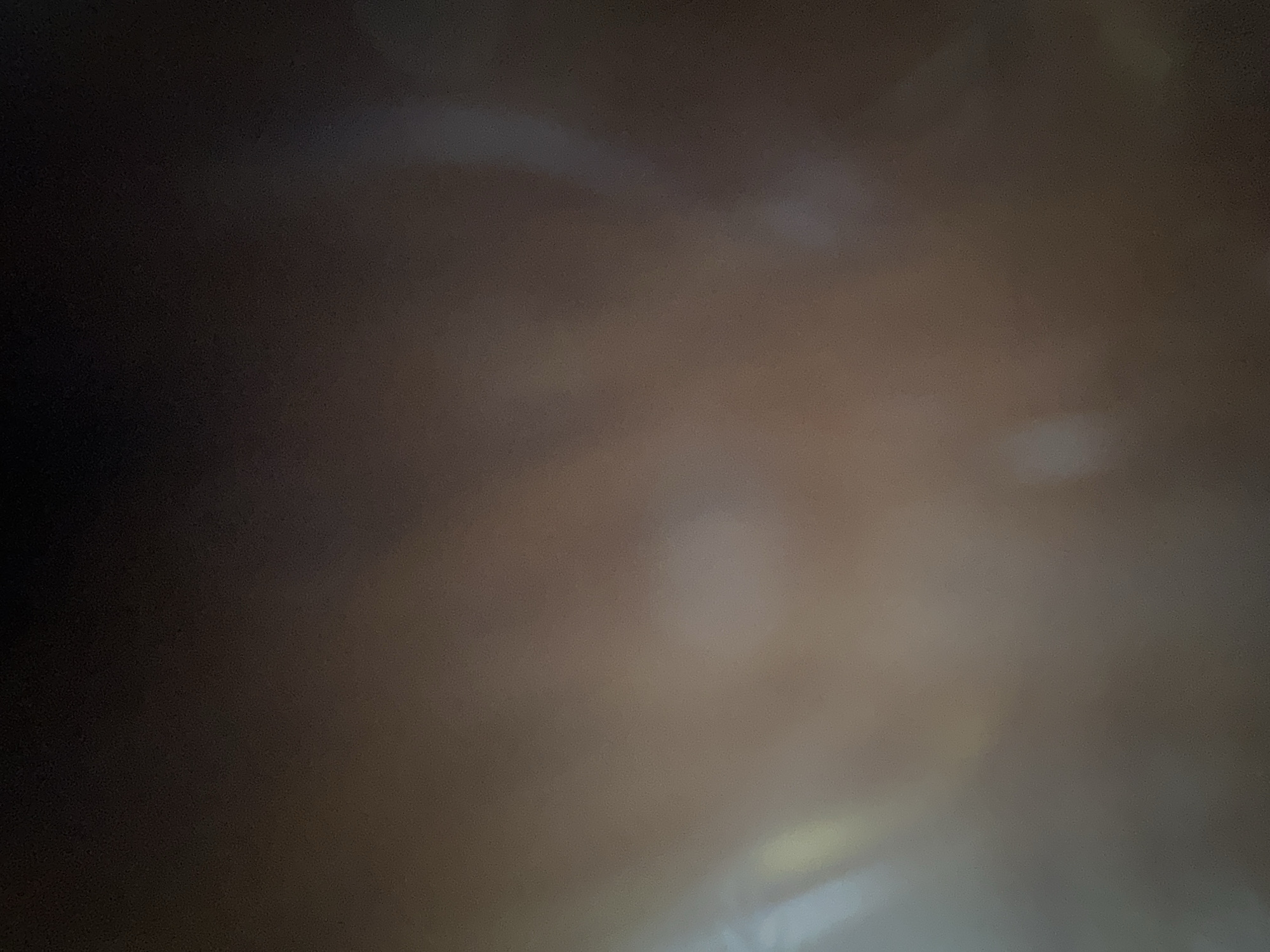 The image is a very dark, out-of-focus, and grainy photograph. It appears to be an indoor scene with very low lighting. There are faint hints of light sources creating bright, blurred areas, possibly reflections or light spills. The colors are muted, primarily shades of brown and black, with some very pale white or light gray areas. No discernible objects, people, or specific environmental details can be identified due to the extreme lack of focus and clarity. It is not possible to determine the location within Belgrade, Serbia, or any other specific details about the scene.